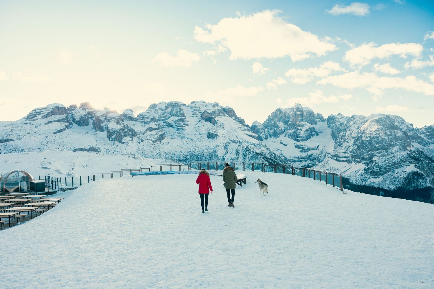 Snow-covered mountain peaks under blue sky with skiers enjoying winter activities at a scenic ski resort.