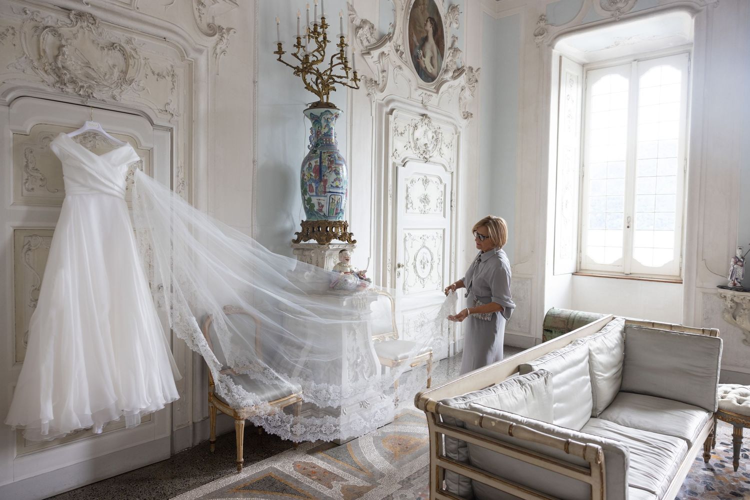 Wedding gown with flowing veil captured in sequence across elegant white baroque interior.