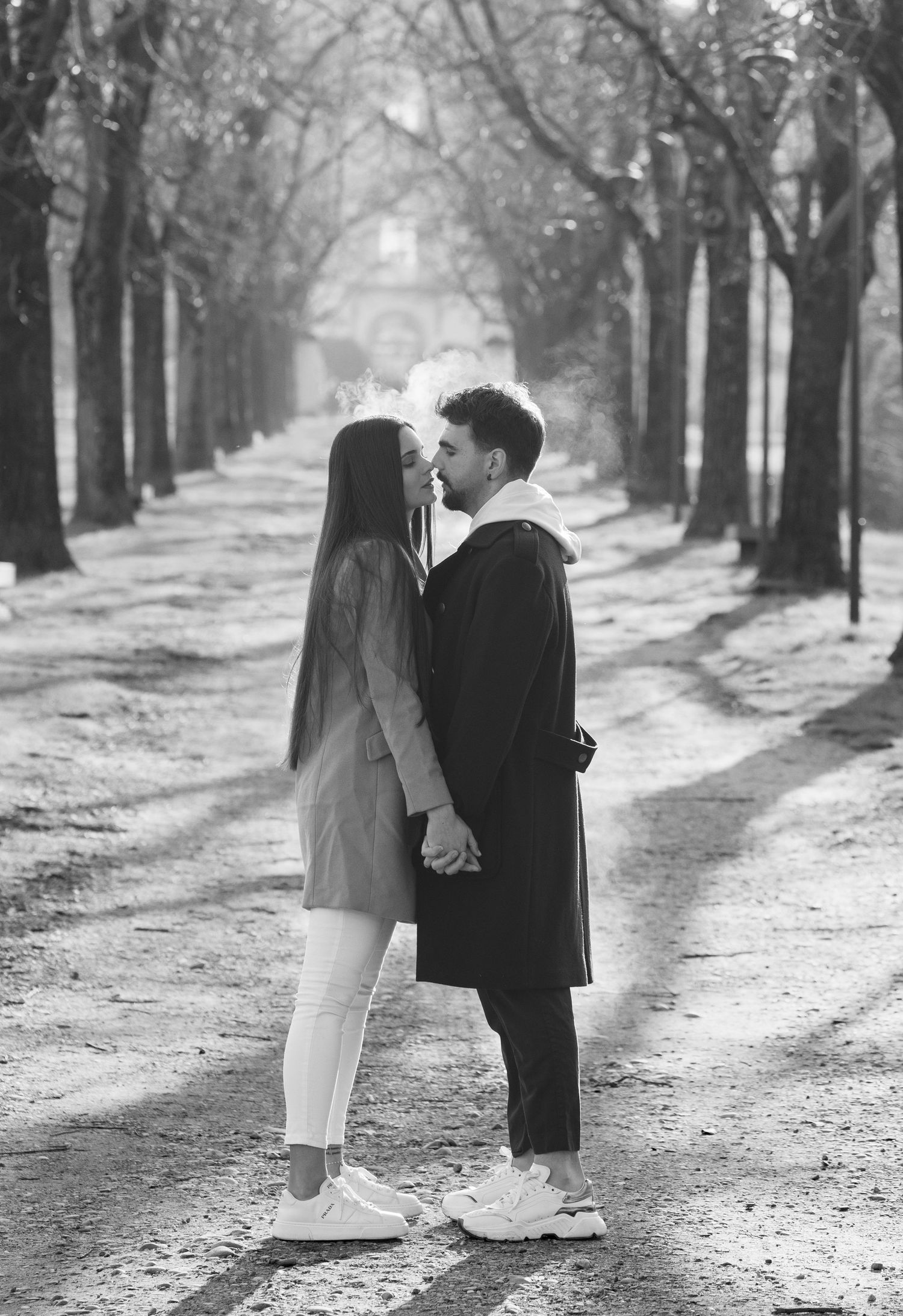 Black and white photos of couple in romantic poses along tree-lined path.
