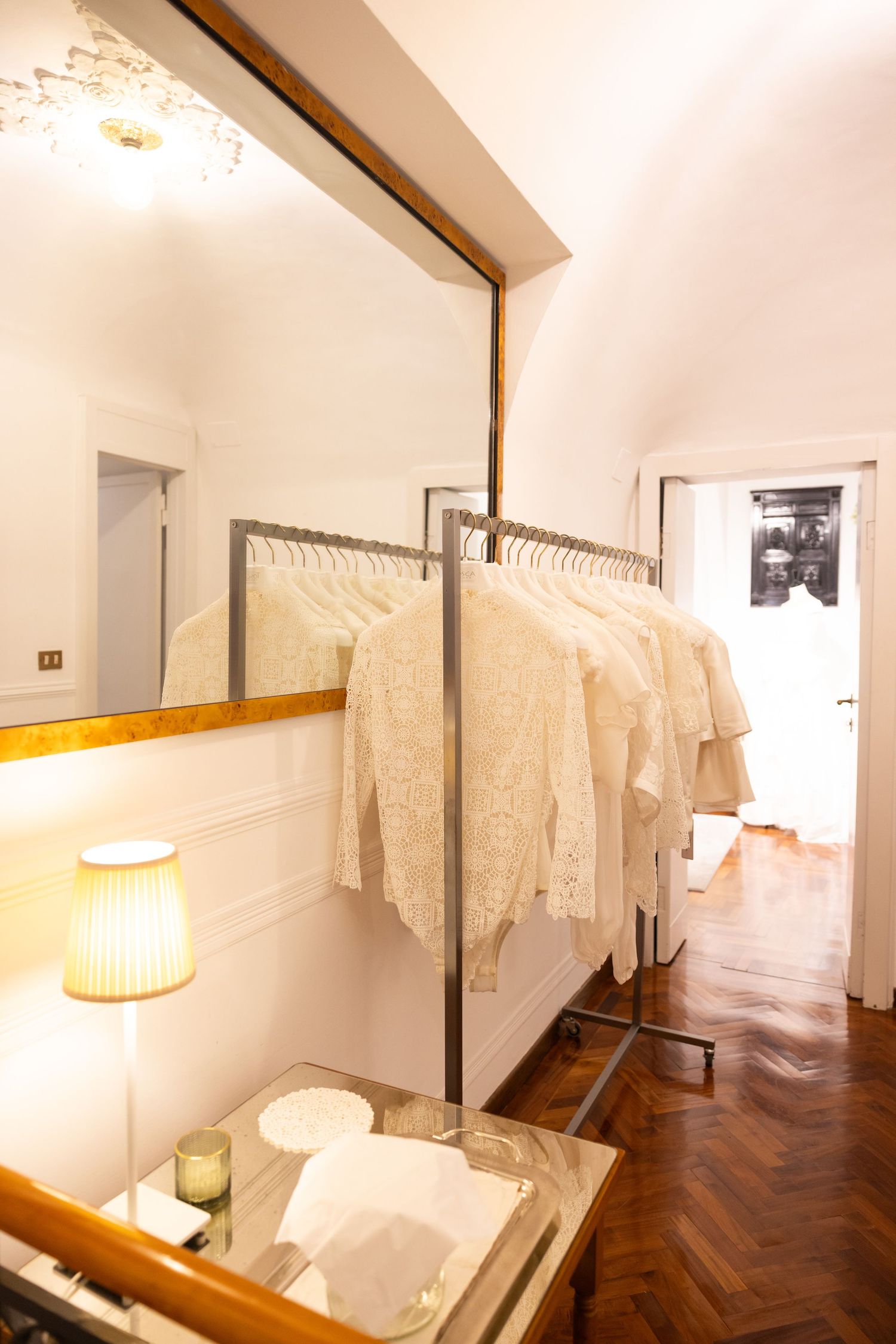 Interior of an elegant bridal boutique with white dresses displayed against cream walls.