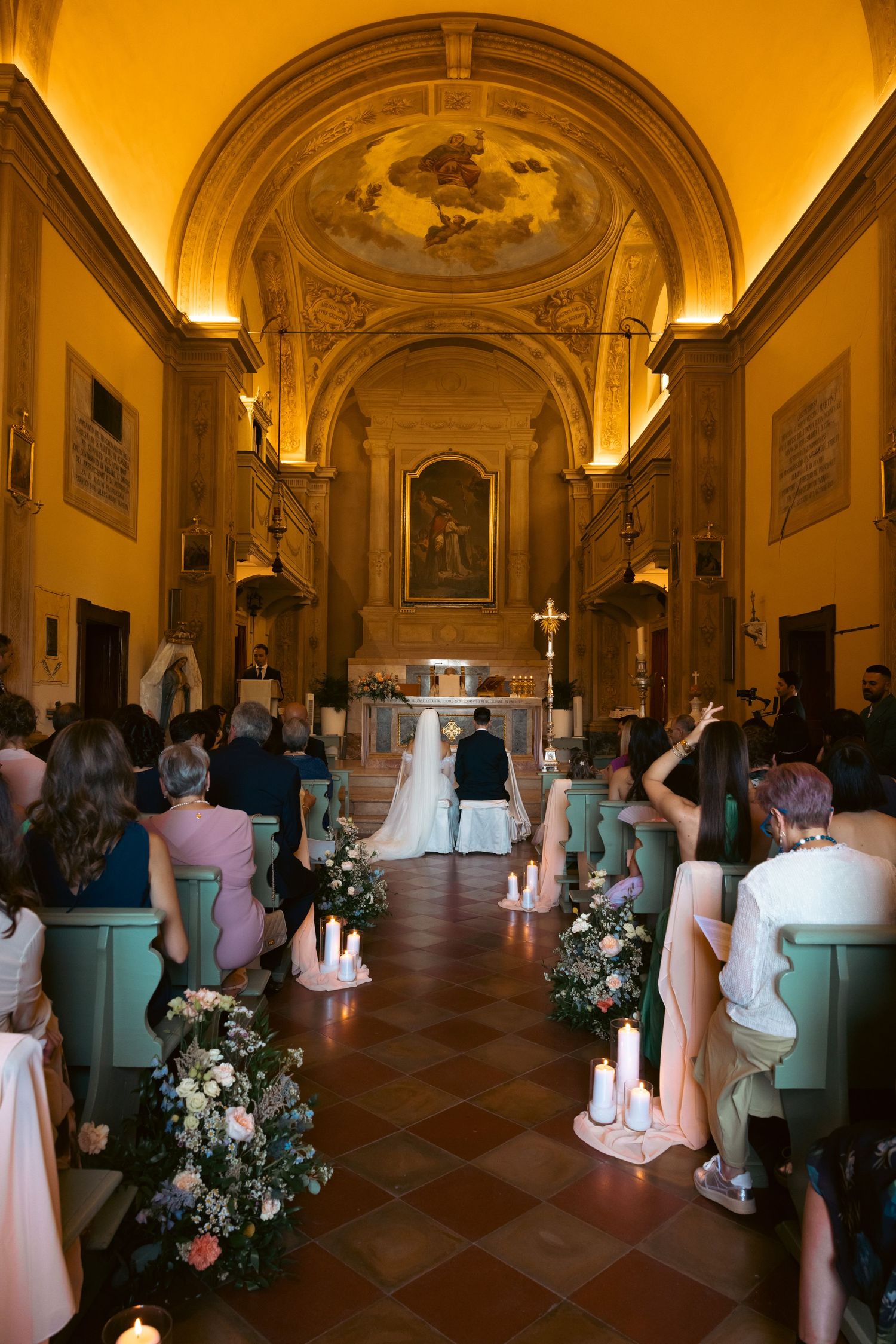 A church interior decorated with floral arrangements and mint-colored chairs for a wedding ceremony.