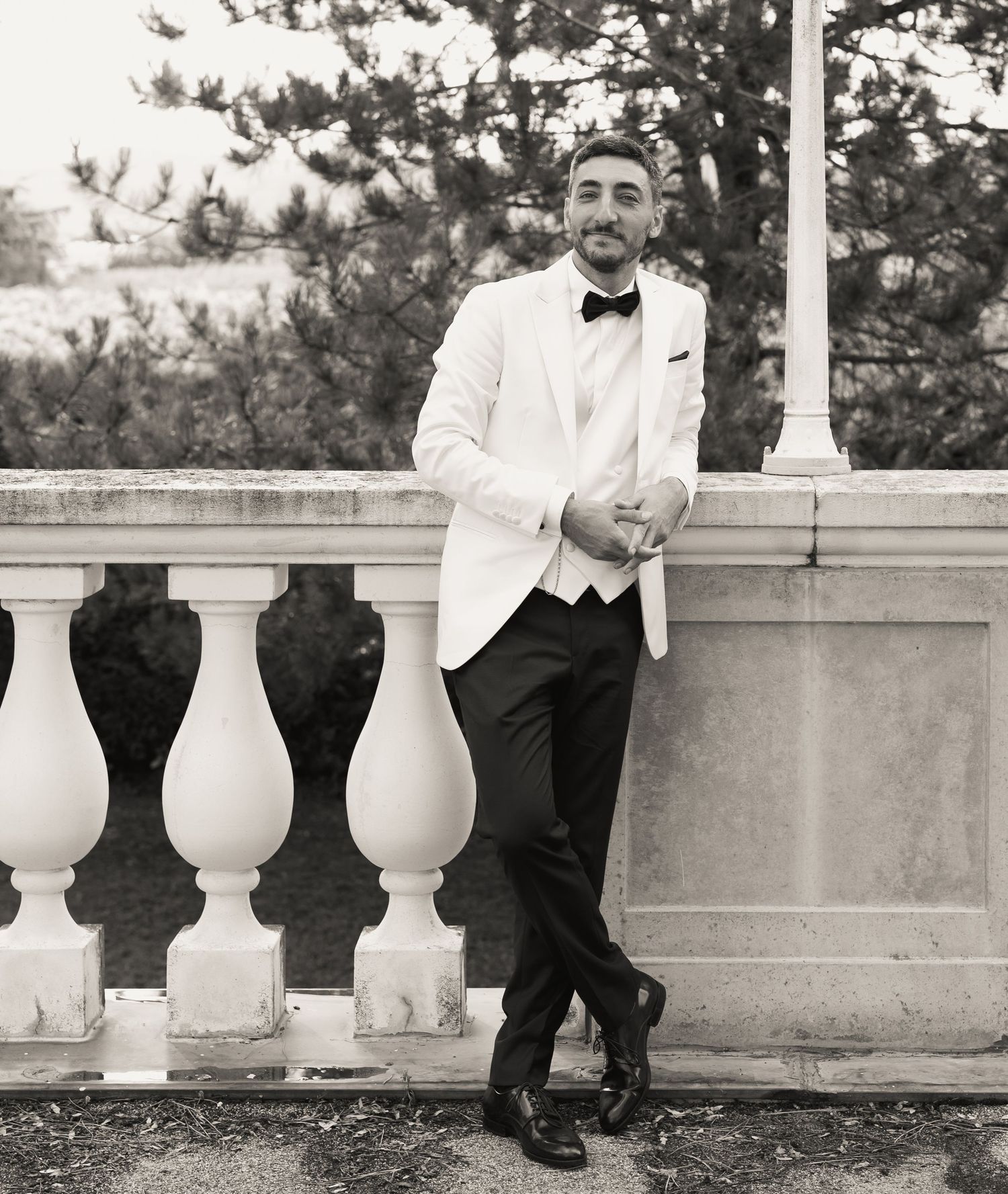 Black and white photo of formal shoes on stone balustrade during wedding photoshoot.