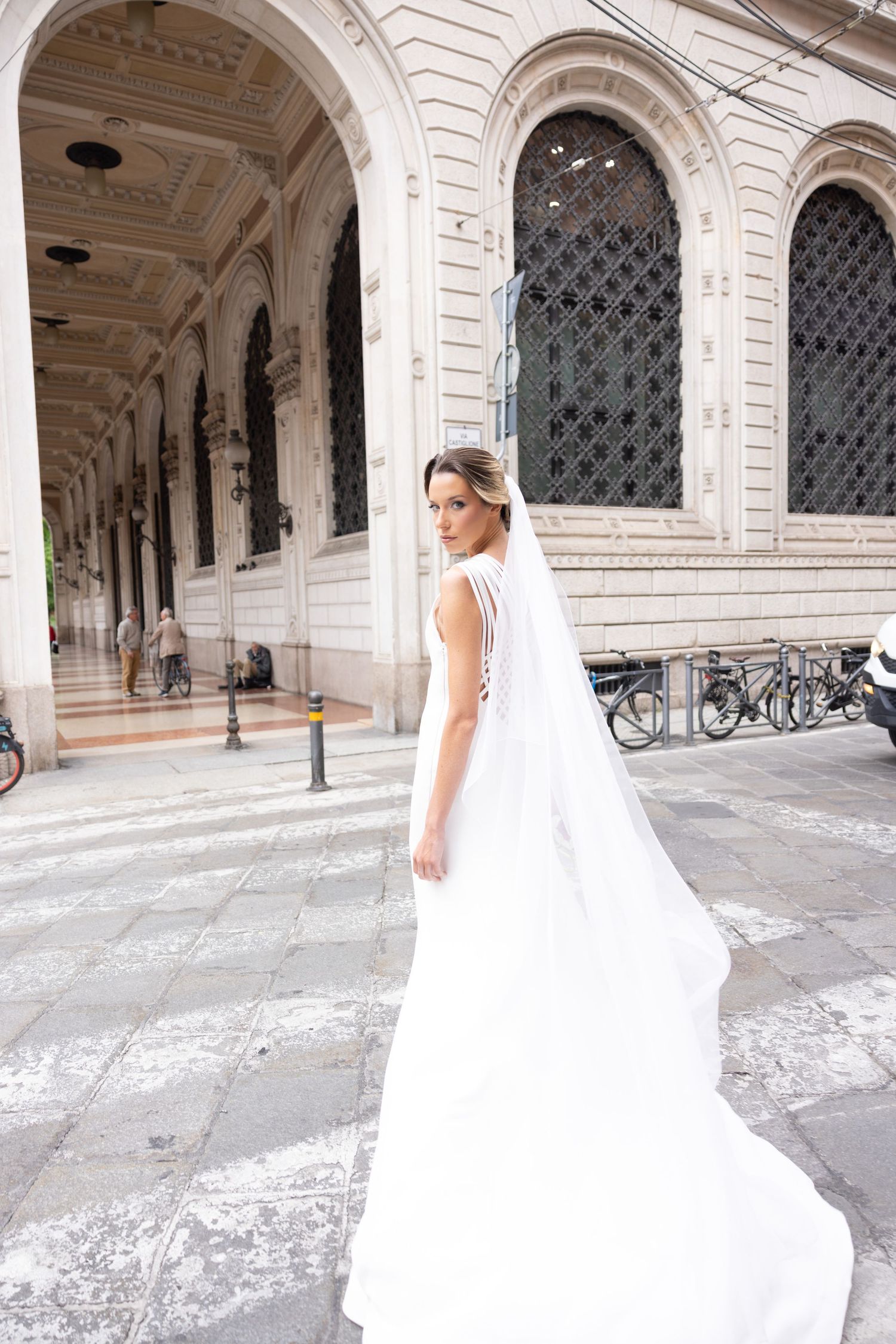 Wedding dress flowing in motion through classical stone archways.