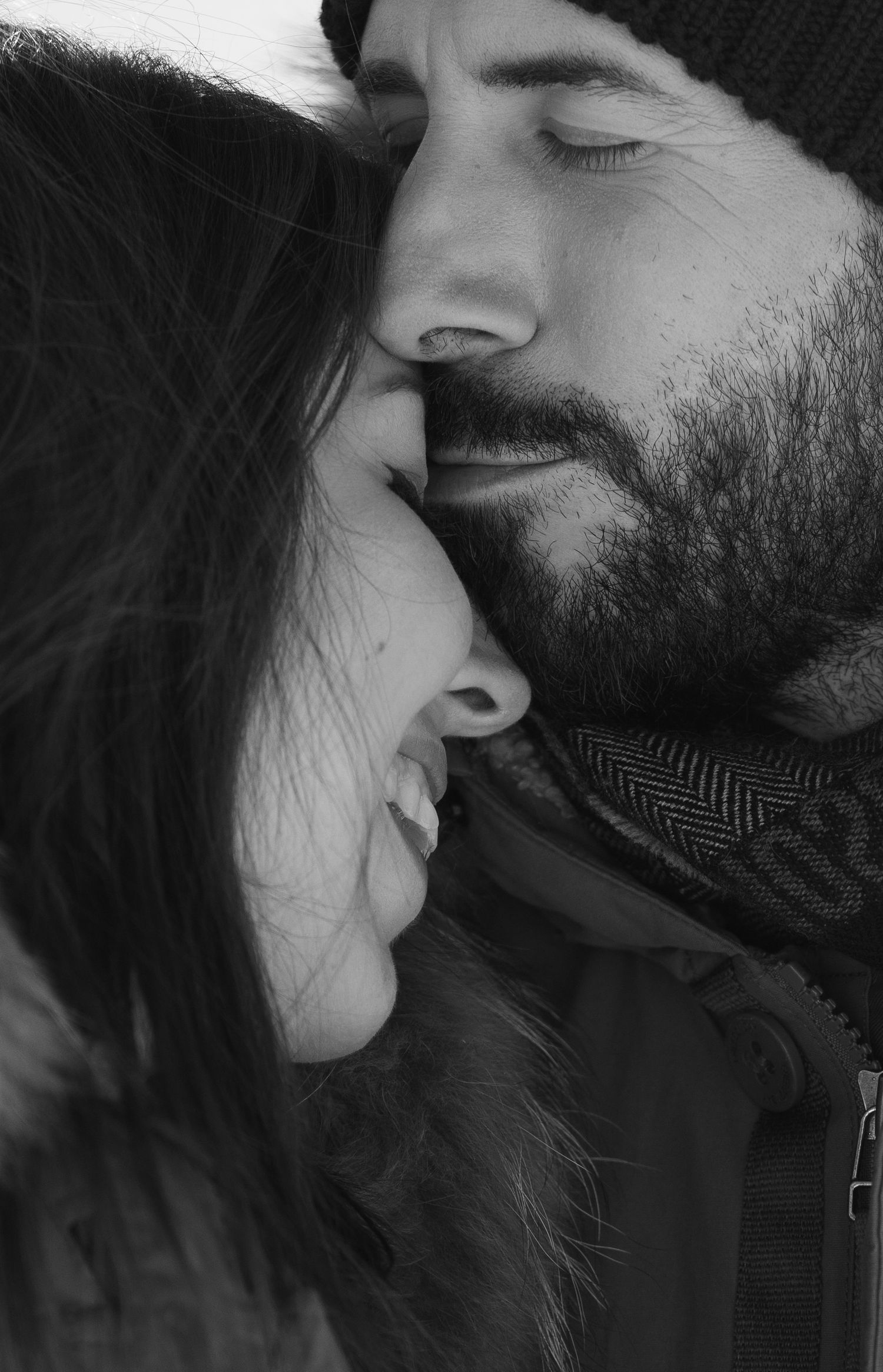 Intimate black and white close-up portrait of a couple sharing a tender winter moment.