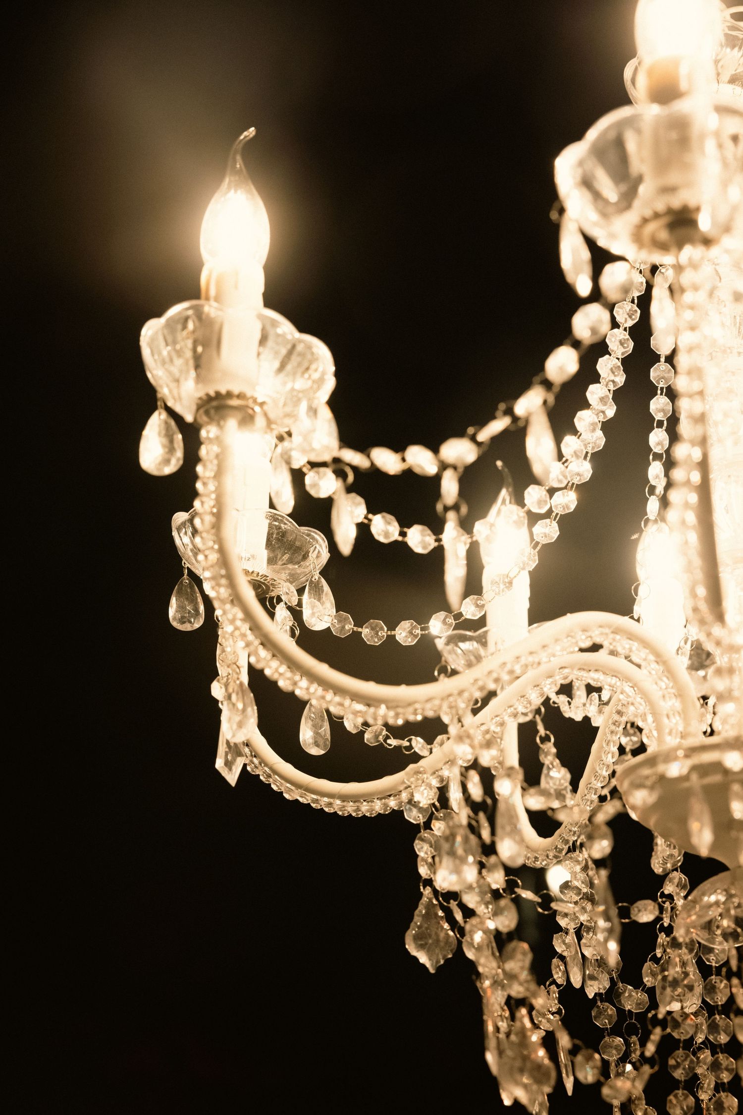 Close-up detail of a crystal chandelier with hanging prisms illuminated in warm light.