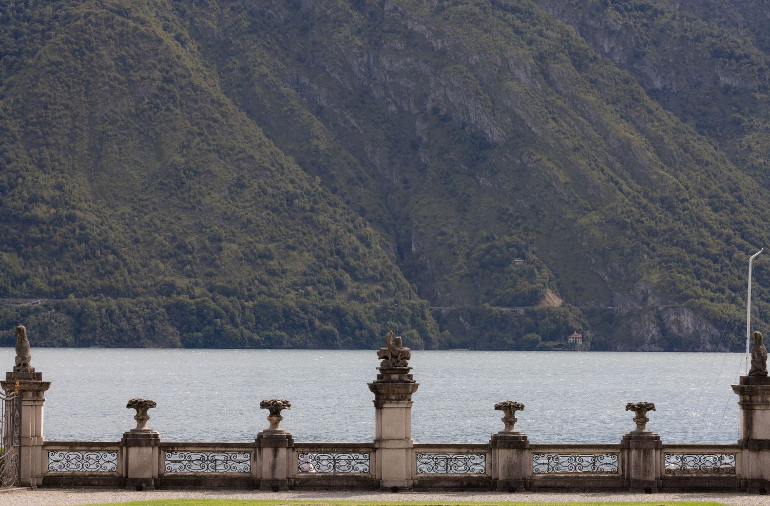 Stone balustrade overlooking mountains and water on a cloudy day.