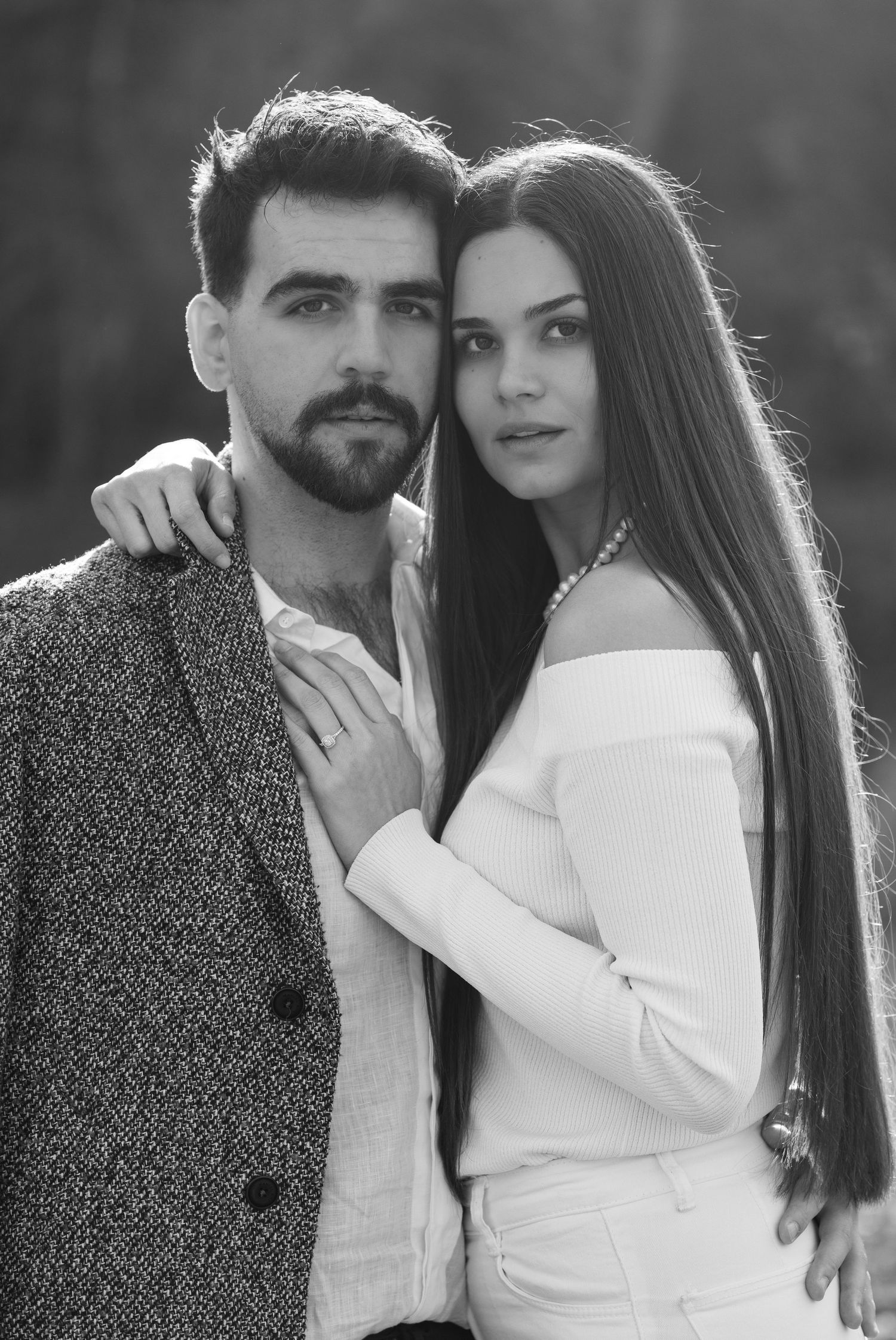 Stylish couple in black and white portrait series showing affectionate poses against natural backdrop.