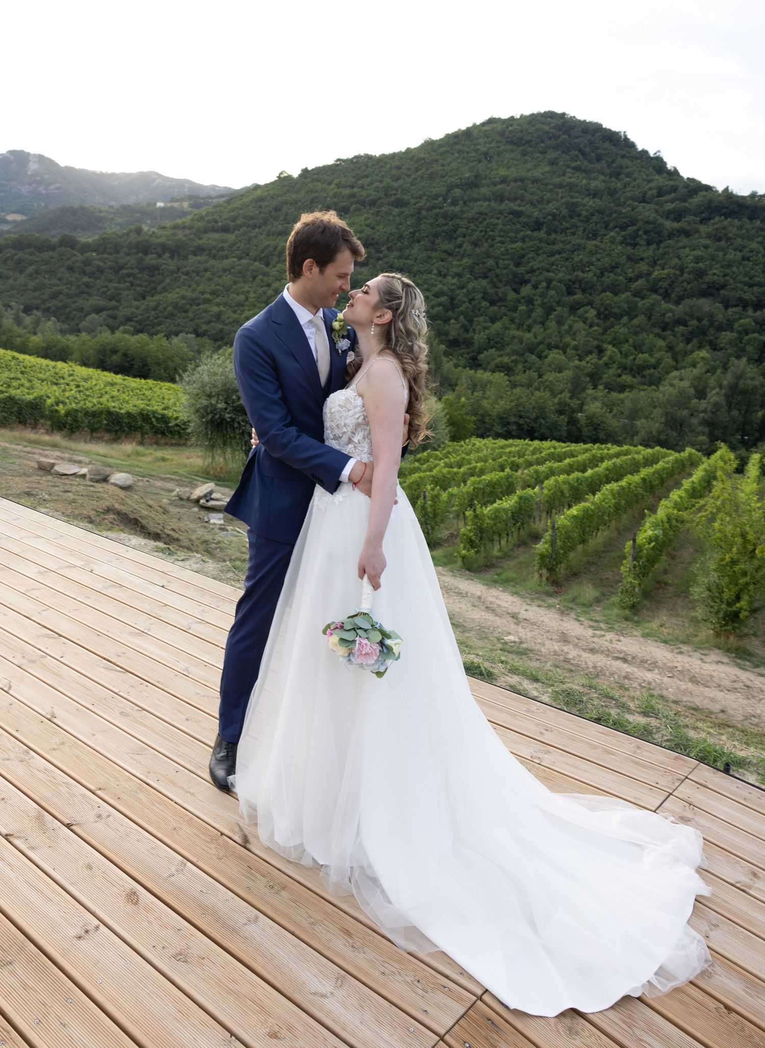 A couple sharing tender moments on a wooden deck surrounded by vineyard views.