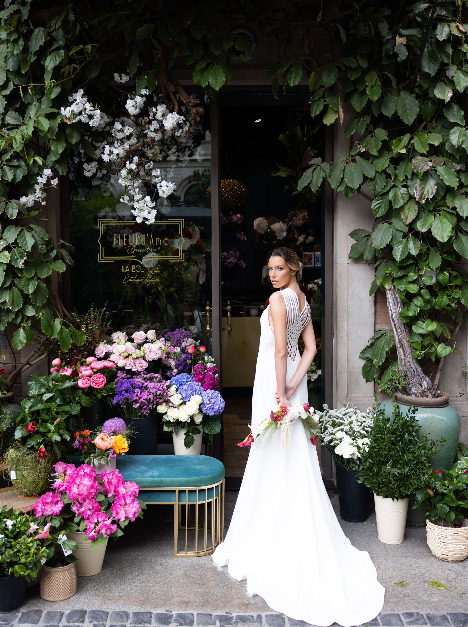 Wedding dress photoshoot along a vine-covered storefront with beautiful flower displays.