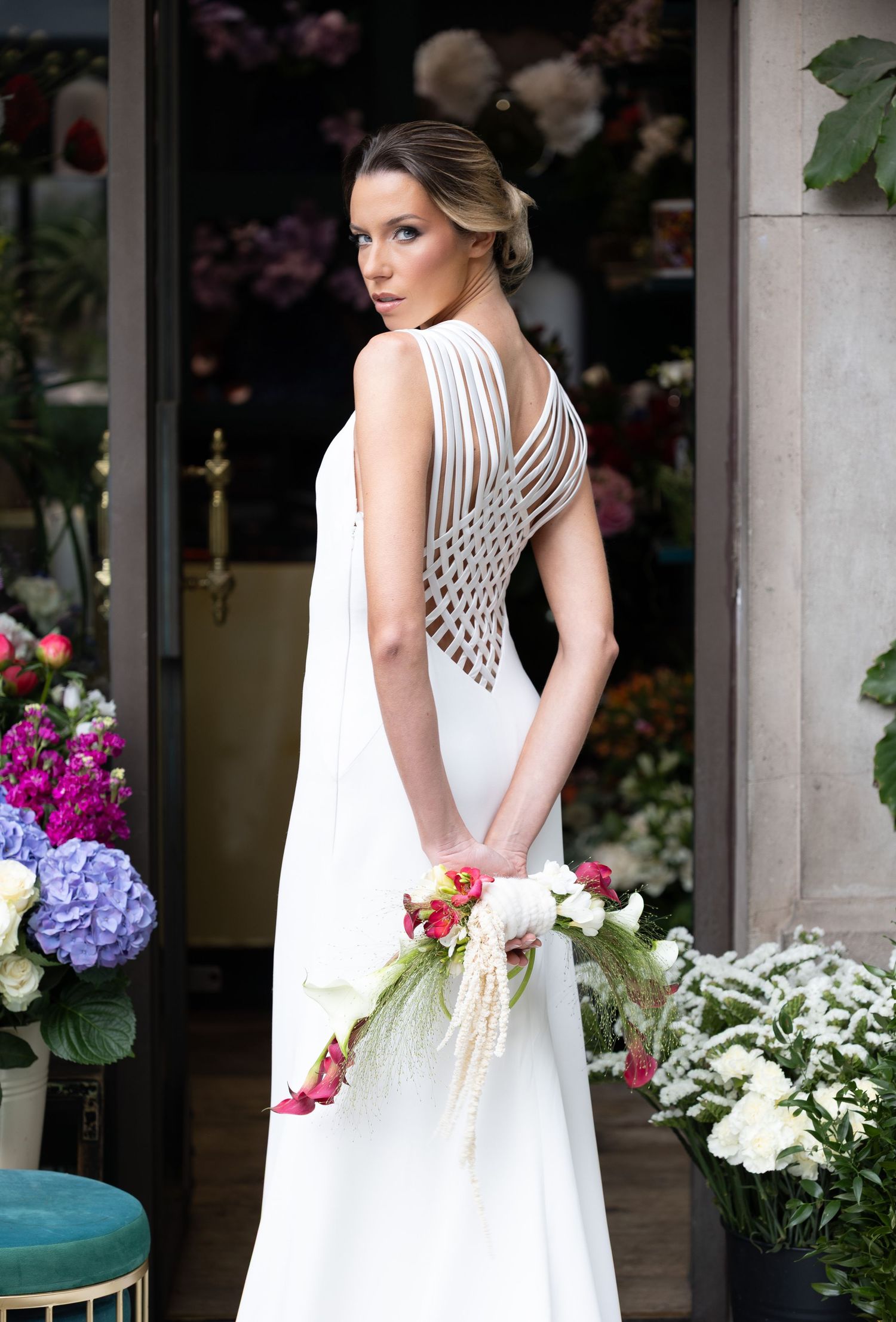 Elegant white dress with lattice detail photographed among colorful garden flowers.