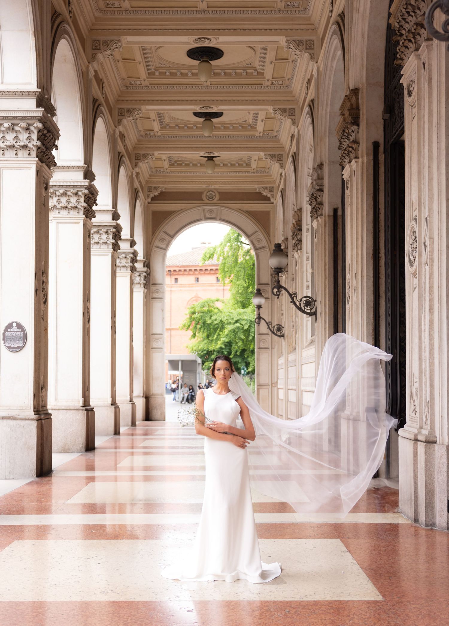 Elegant white marble colonnade hallway with ornate architectural details and natural lighting.