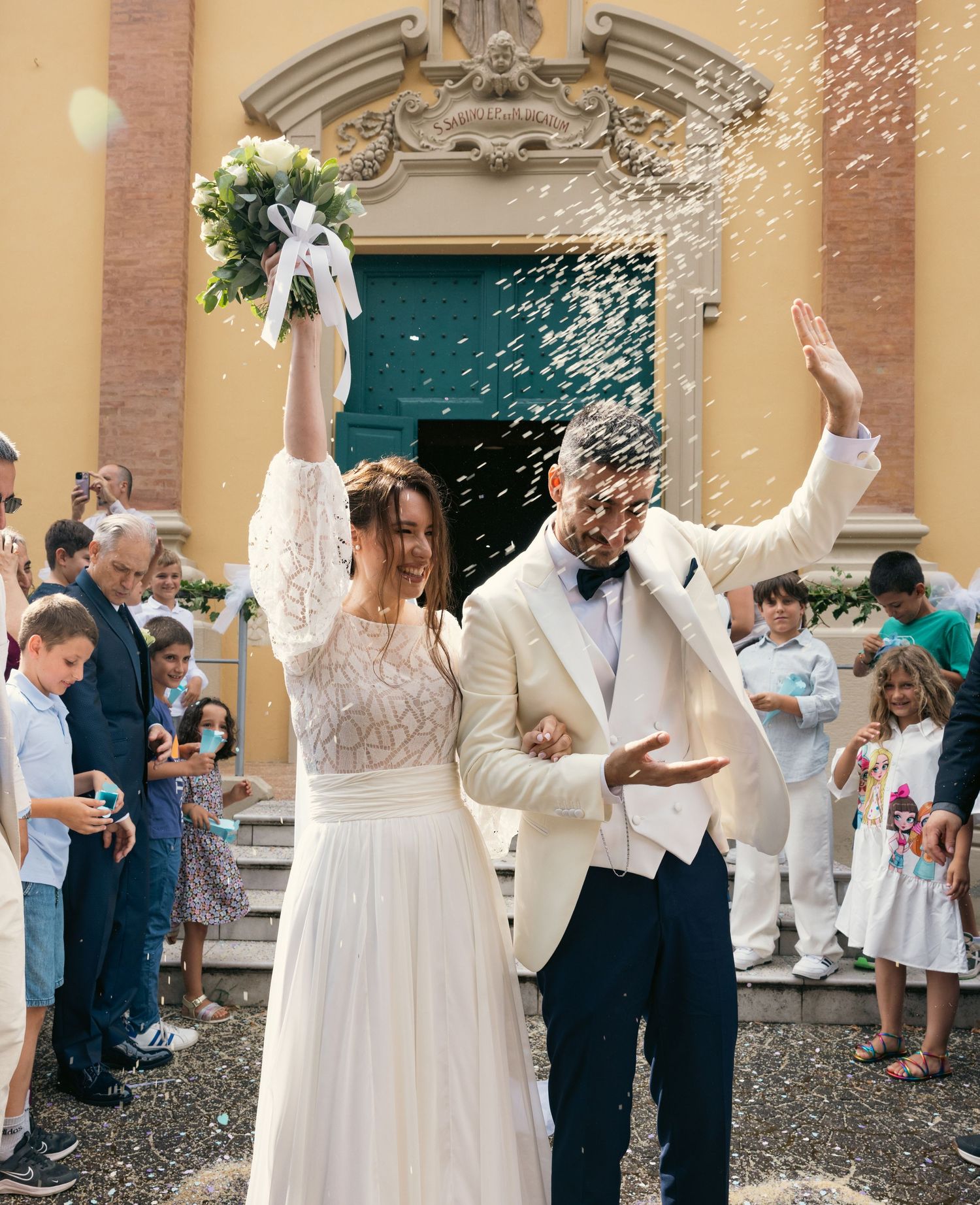 Newlyweds celebrate outside a church as guests shower them with confetti.