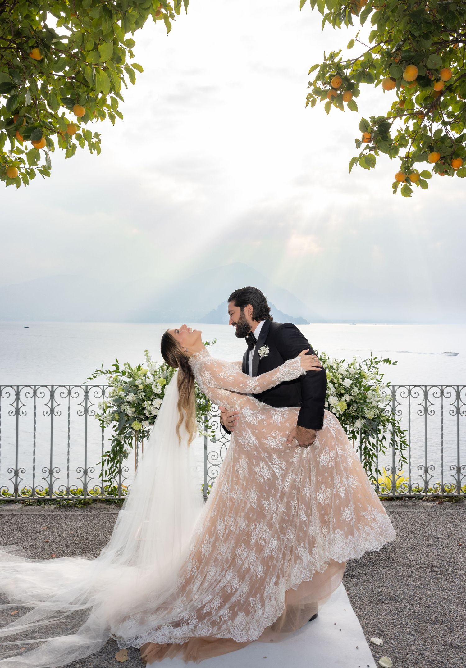 Romantic wedding dance sequence captured against a lakeside backdrop with ornate iron railings.