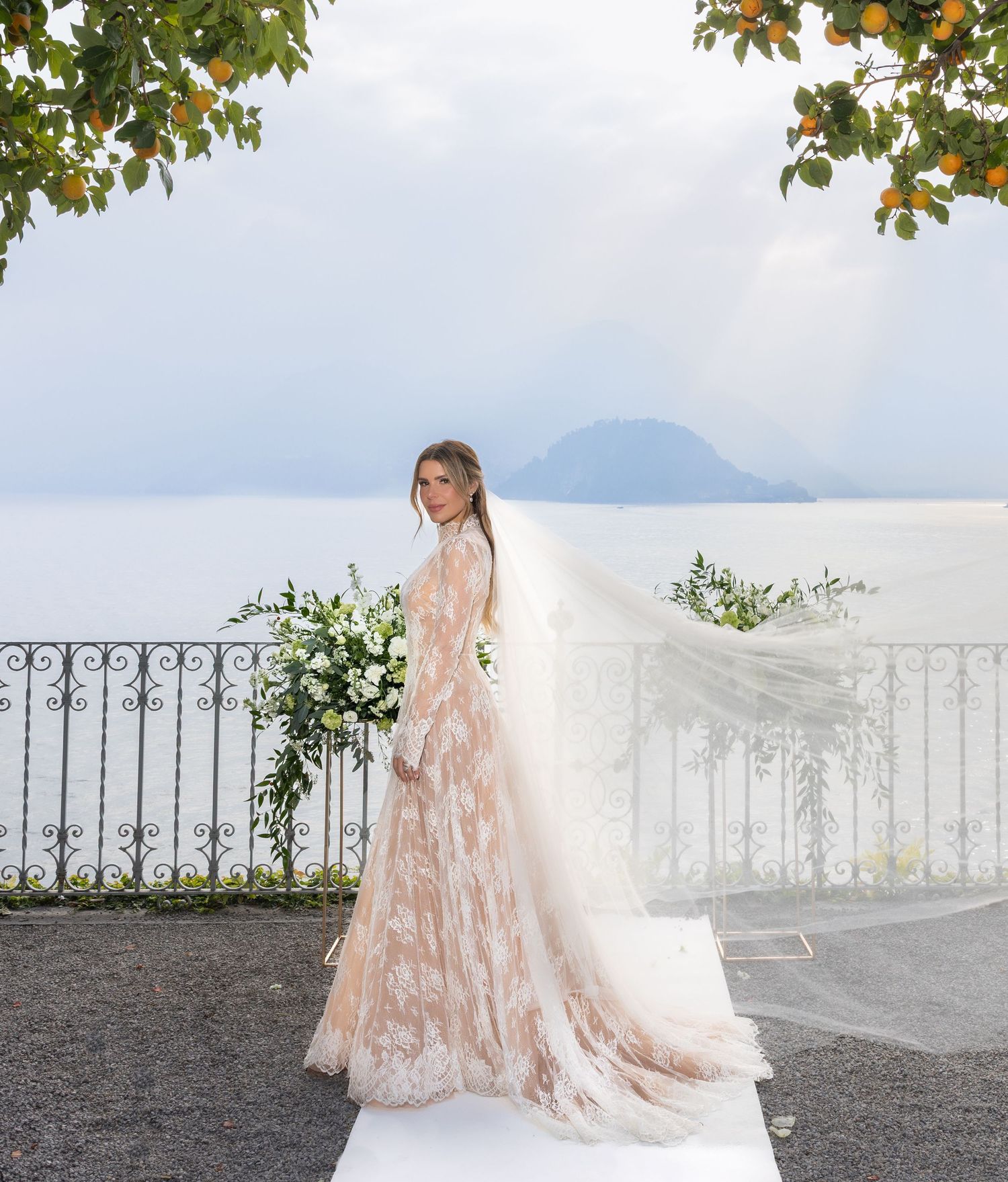 Romantic bridal portrait on a terrace overlooking mountains with an ornate iron railing backdrop.