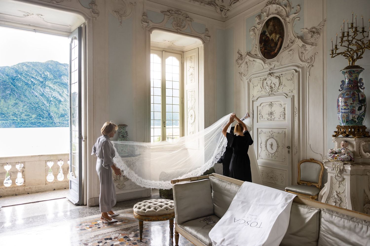 Ornate white room with decorative moldings, balcony views, and elegant architectural details.
