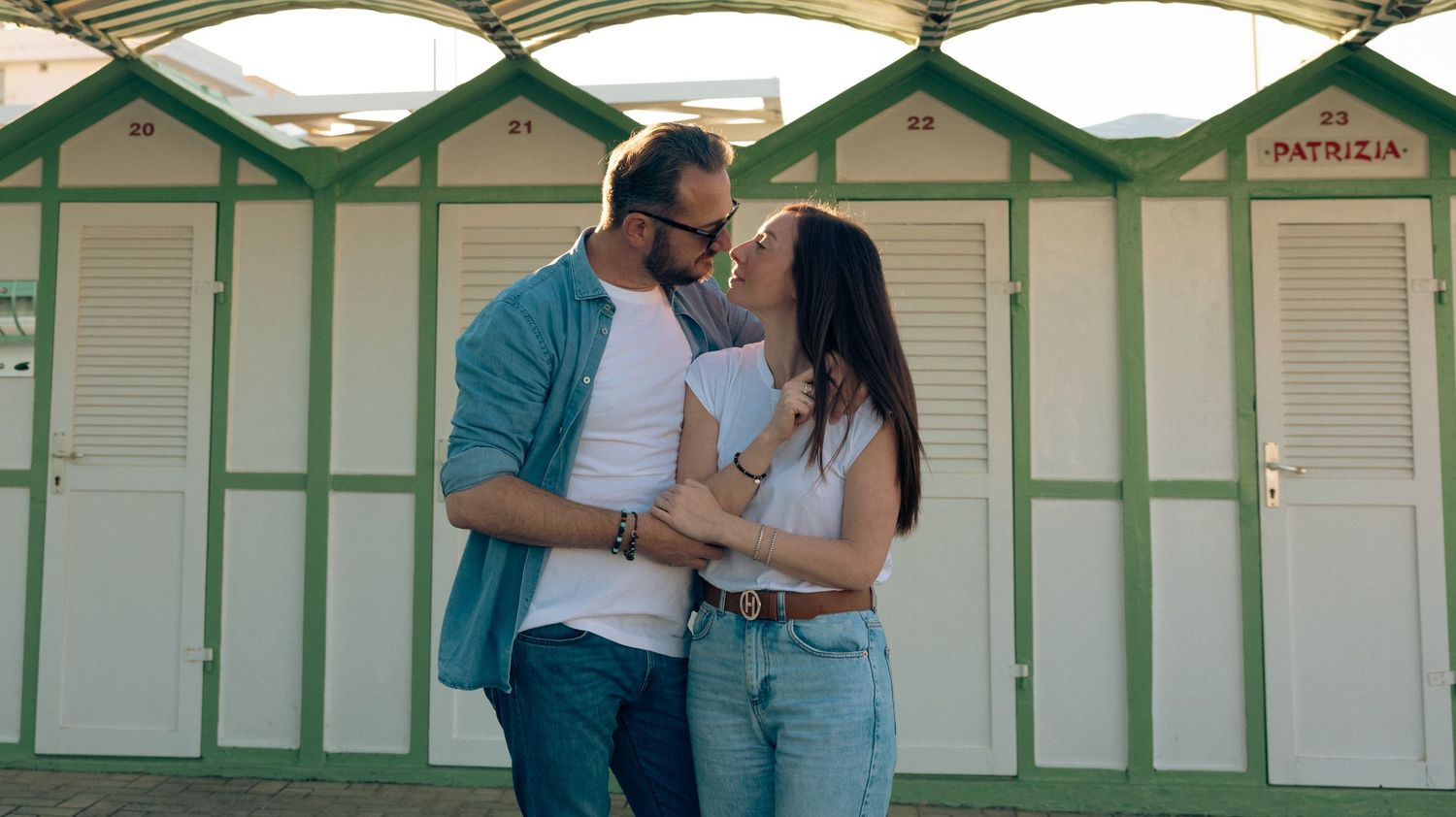 Couple sharing an intimate moment in front of beach changing rooms.