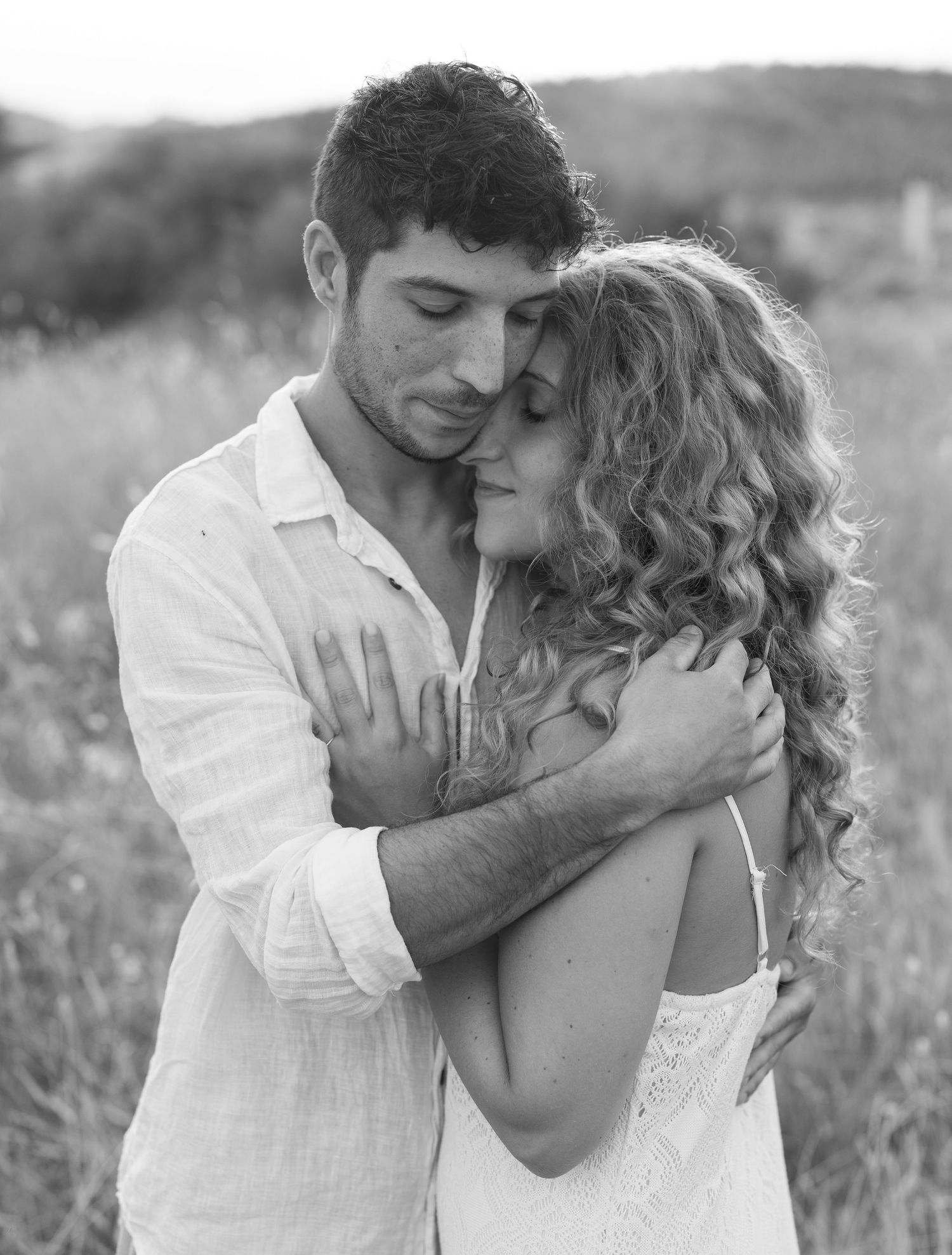 Romantic couple sharing tender moments in a sunlit meadow during golden hour.