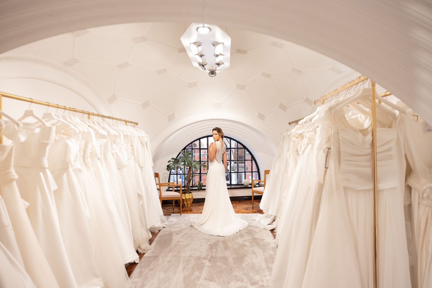 Wedding dress display room with vaulted ceilings and rows of white gowns.
