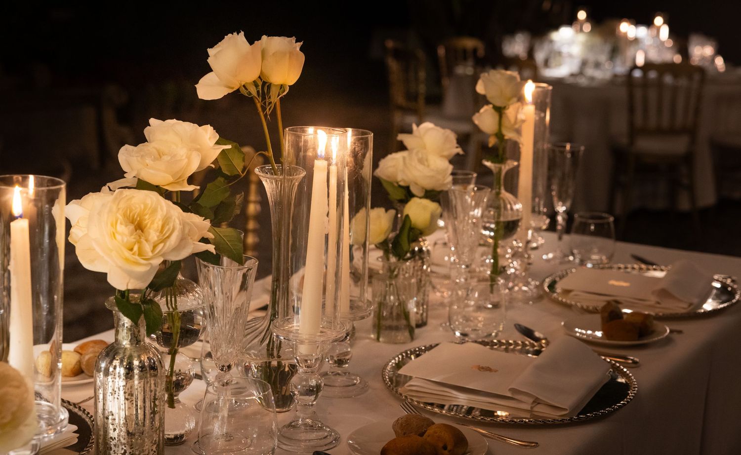 Wedding reception table decorated with white floral centerpieces and crystal glassware.