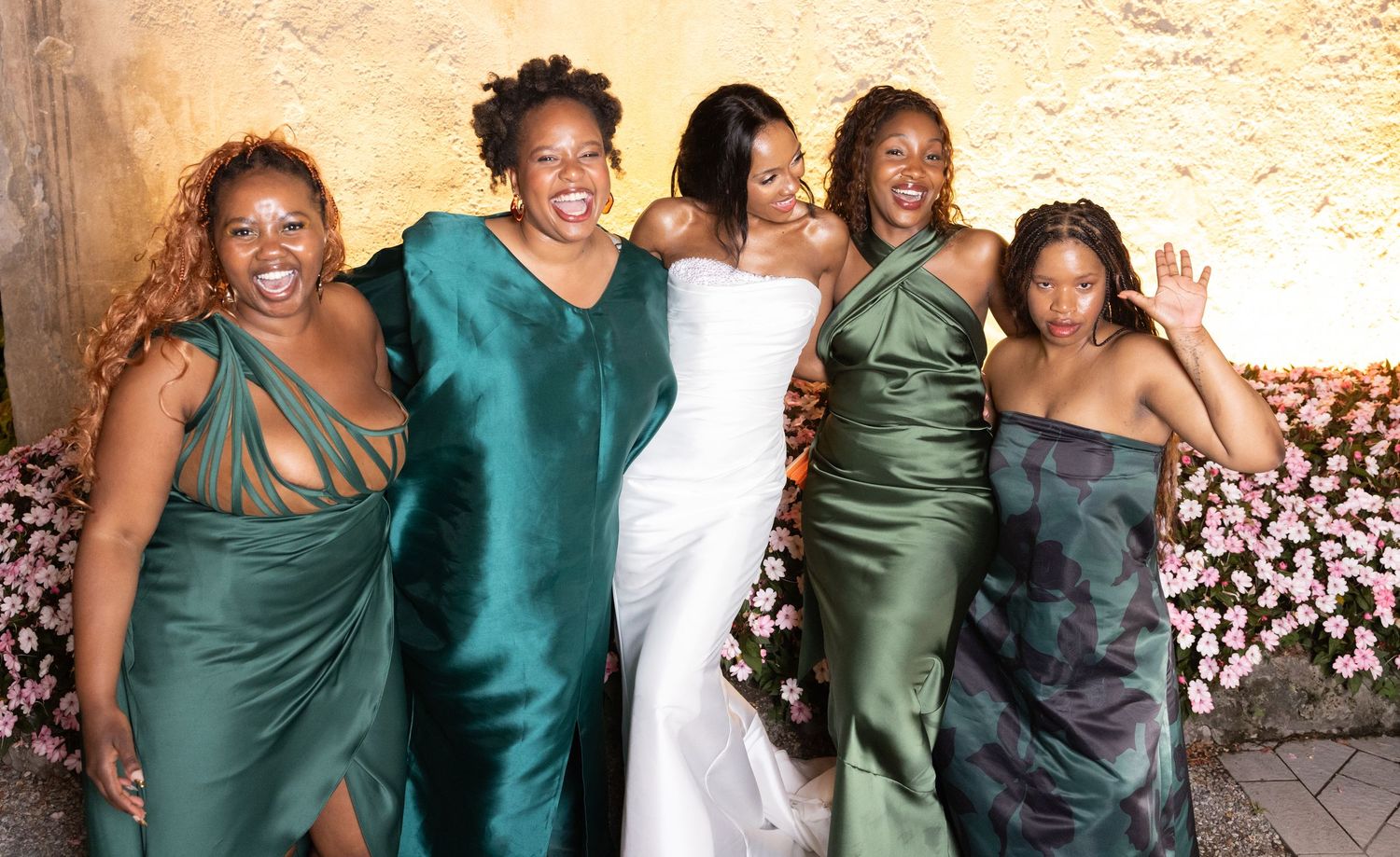 A group wearing coordinated emerald green and teal formal attire poses together at an event.