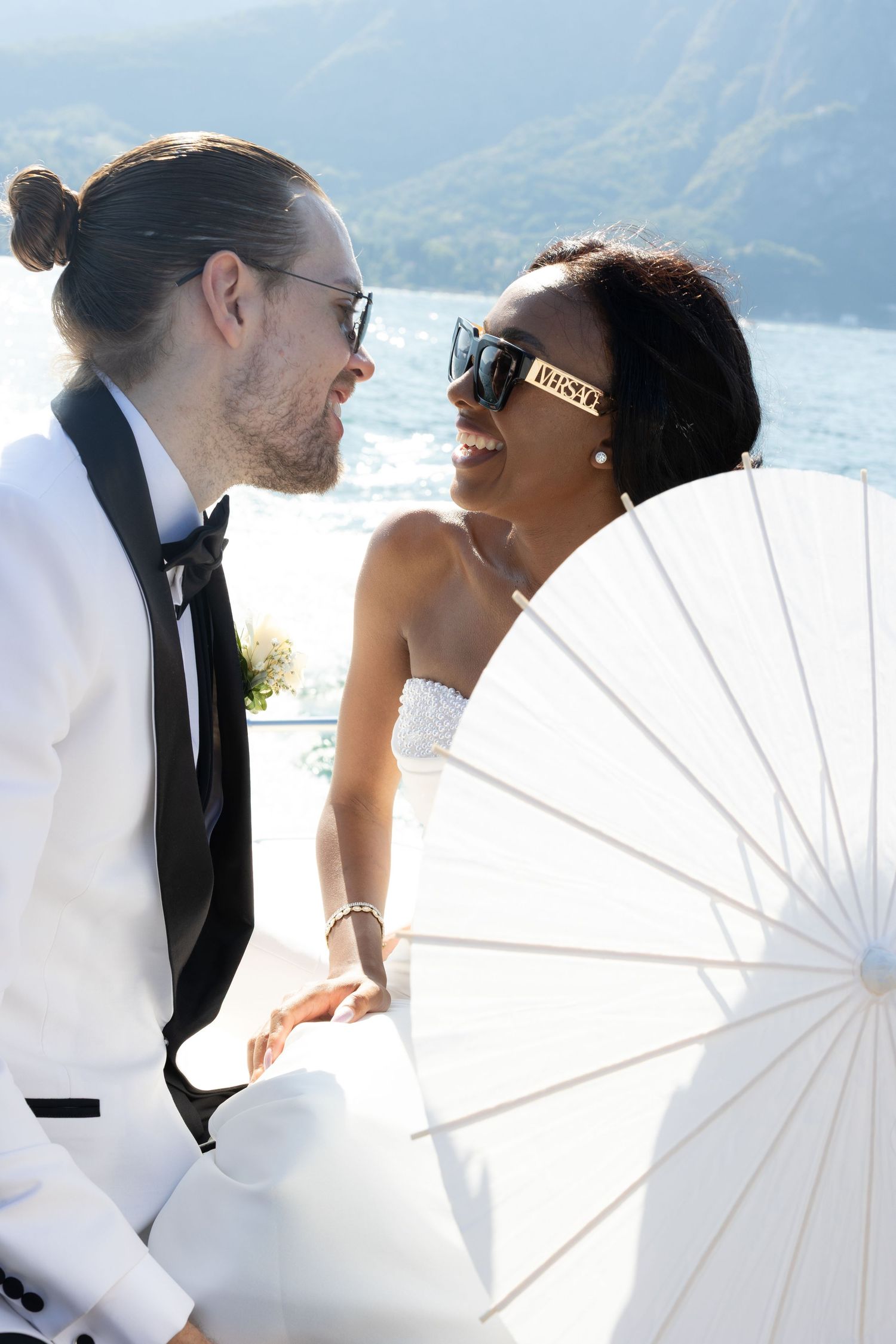 A romantic wedding photo series with a white parasol against a scenic mountain backdrop.