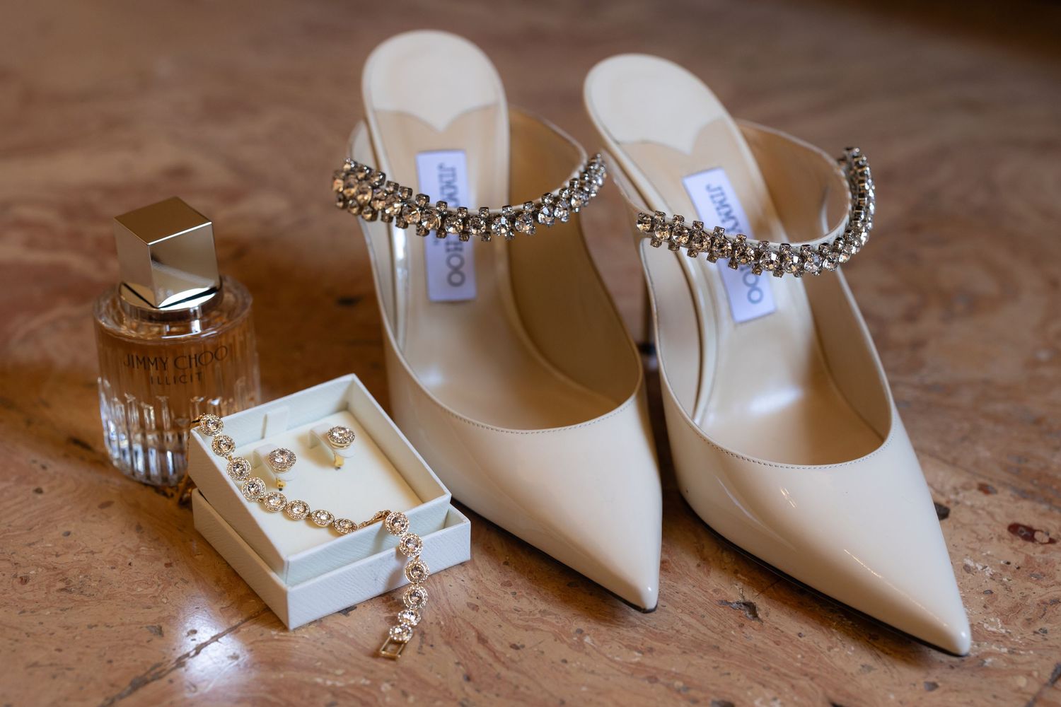Elegant white pointed-toe bridal heels with pearl necklace accessories arranged on wooden surface.
