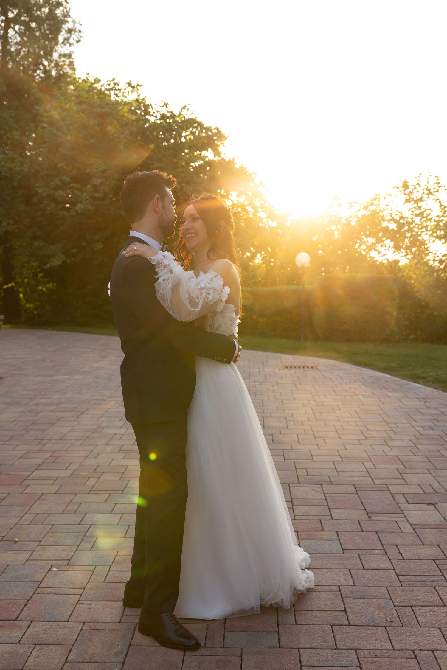 Couple dancing together on a brick patio during golden hour.