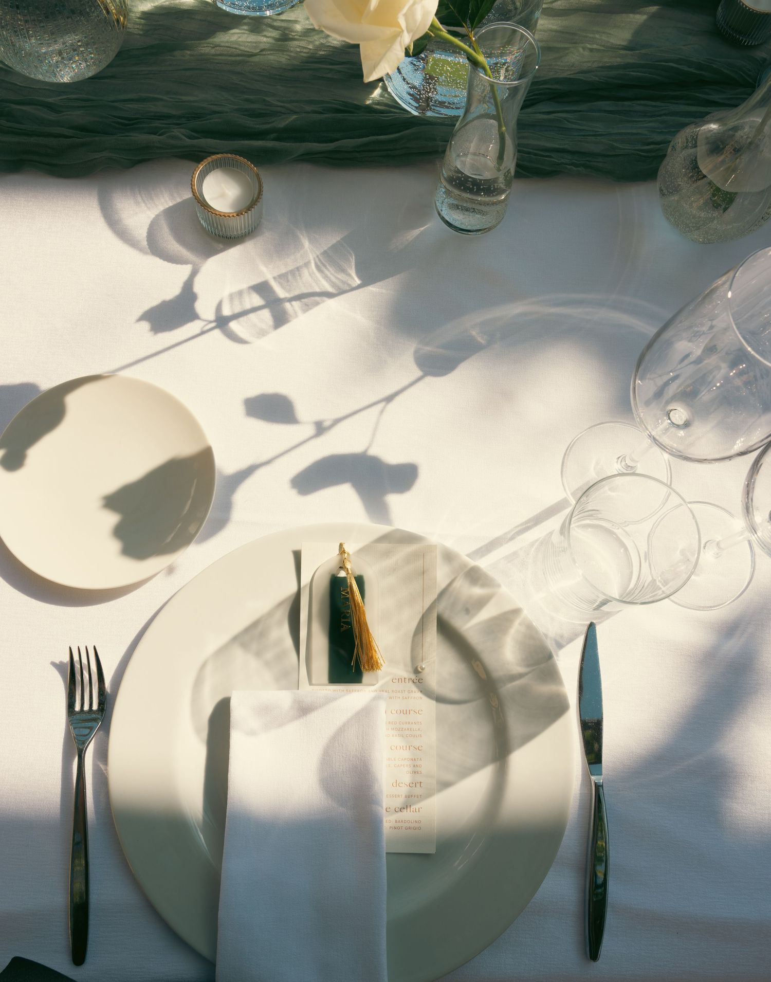 Artistic arrangement of table settings with dramatic shadows cast across a white tablecloth.