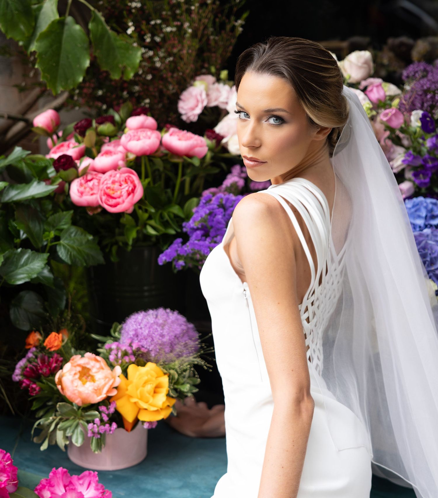 Romantic bridal portrait series with flowing veil and stunning floral garden backdrop.