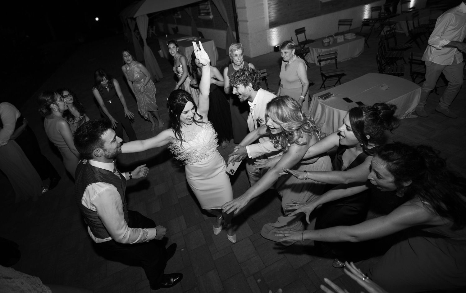 Wedding reception dance floor with guests celebrating in a dark venue.