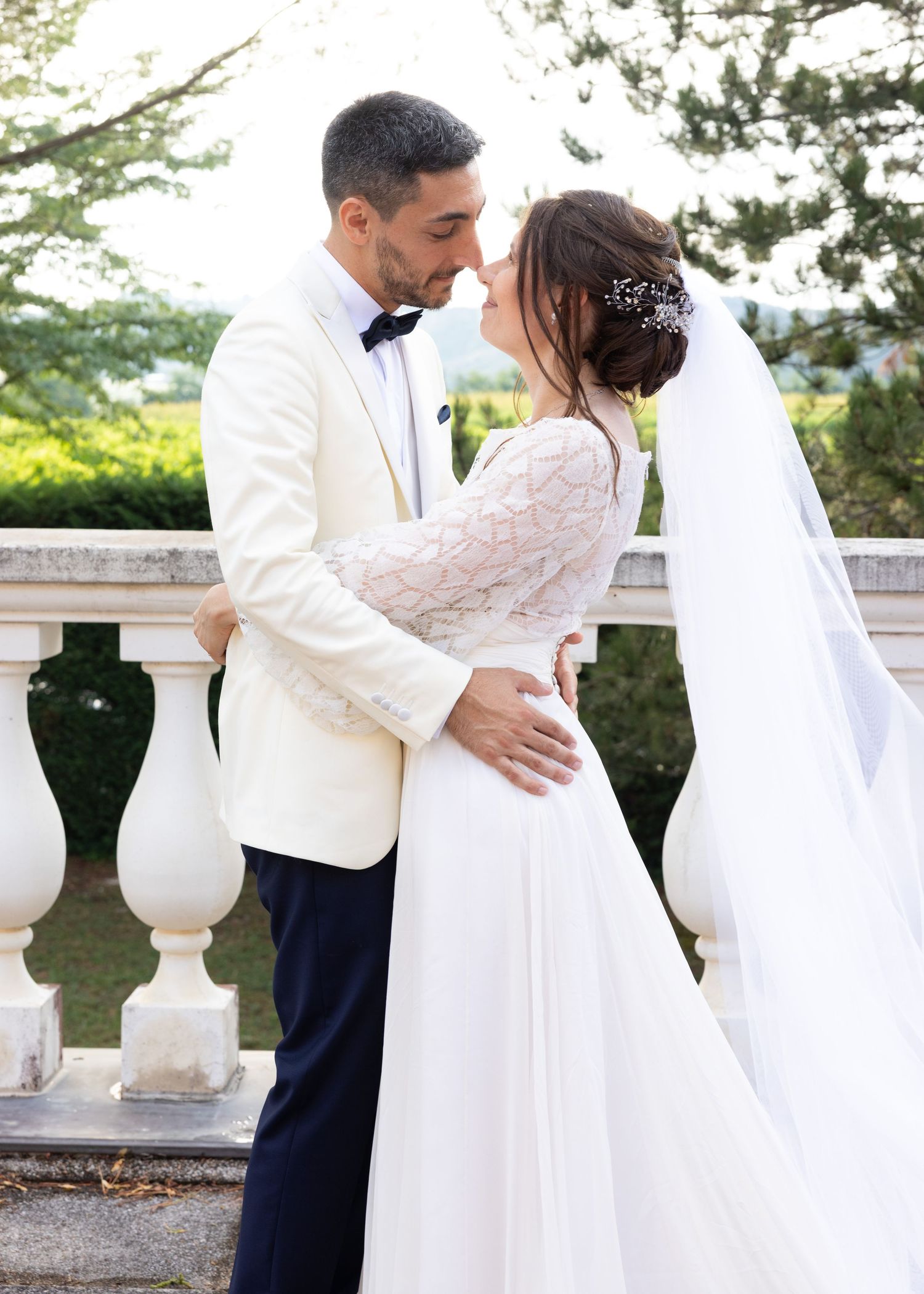 Romantic moment between newlyweds on an elegant balcony with stone pillars.