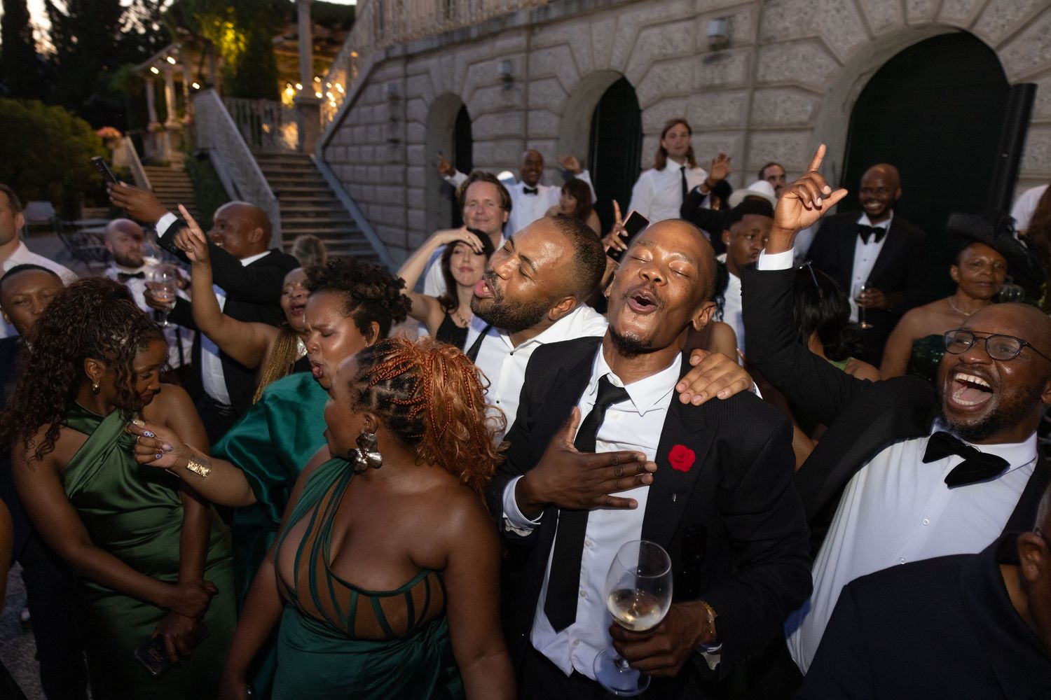 A lively crowd of people dancing and celebrating at a party or event in an indoor venue.