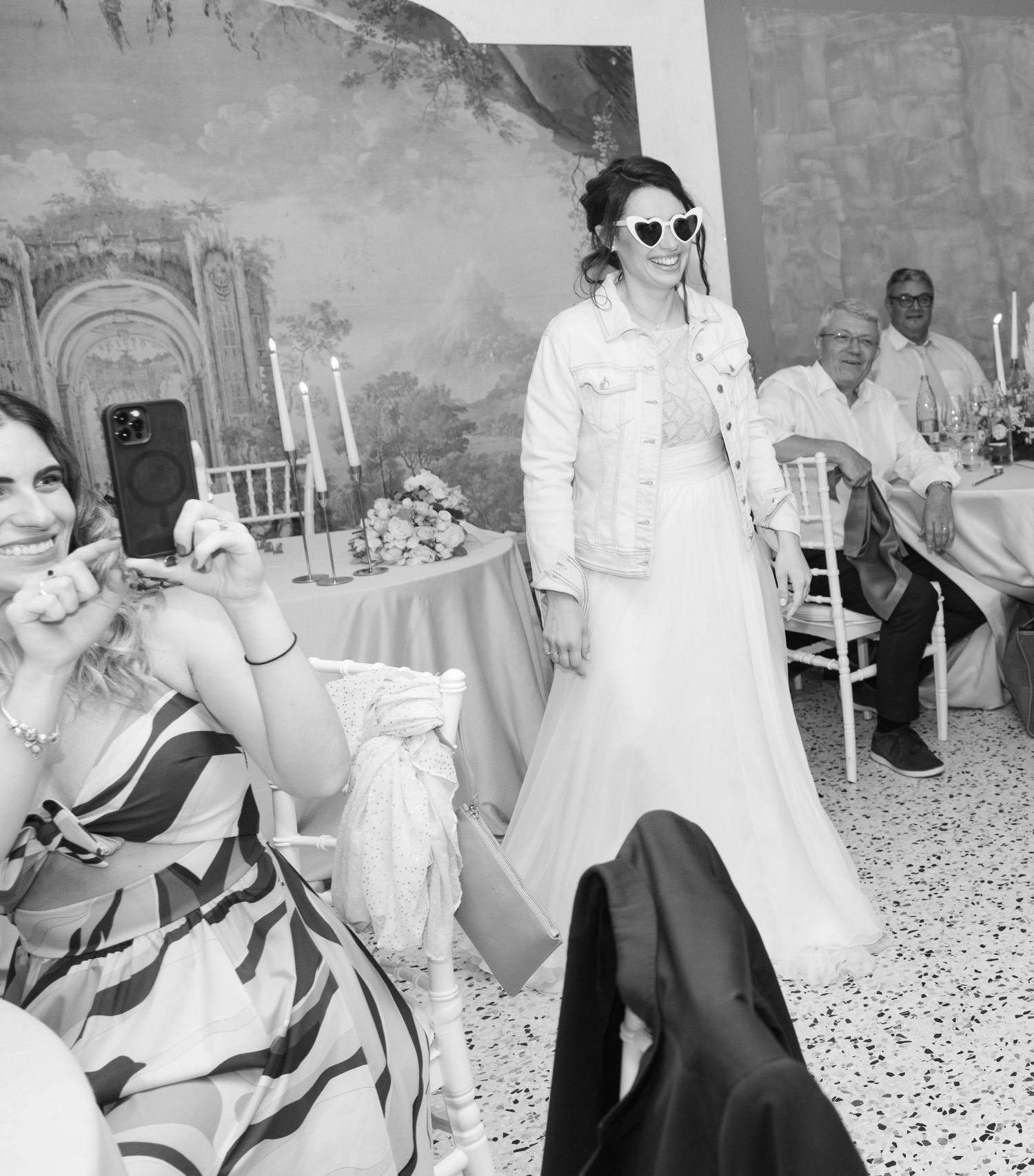 Black and white photo of wedding guests relaxing in chairs during an outdoor reception.