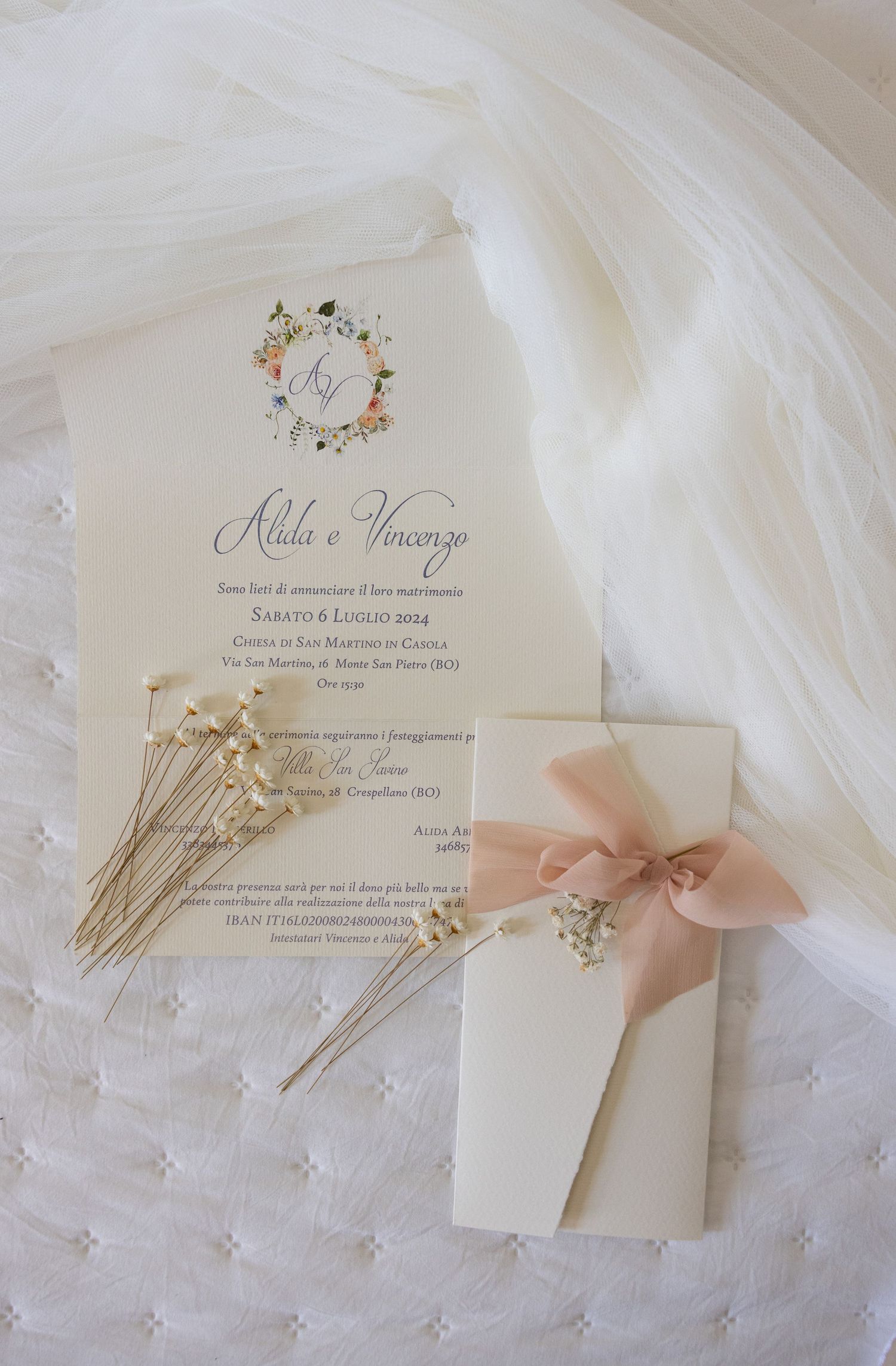 Wedding stationery suite with blush pink bows and pearl pins on white tulle fabric.