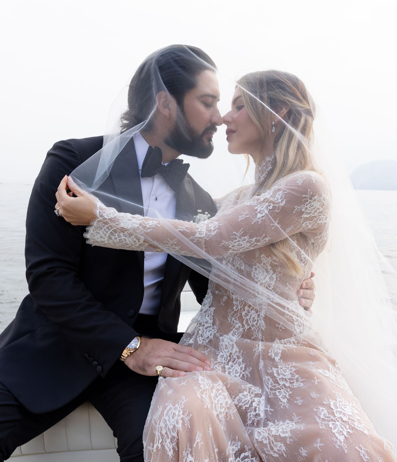 Romantic wedding couple sharing tender moments against a misty coastal backdrop.
