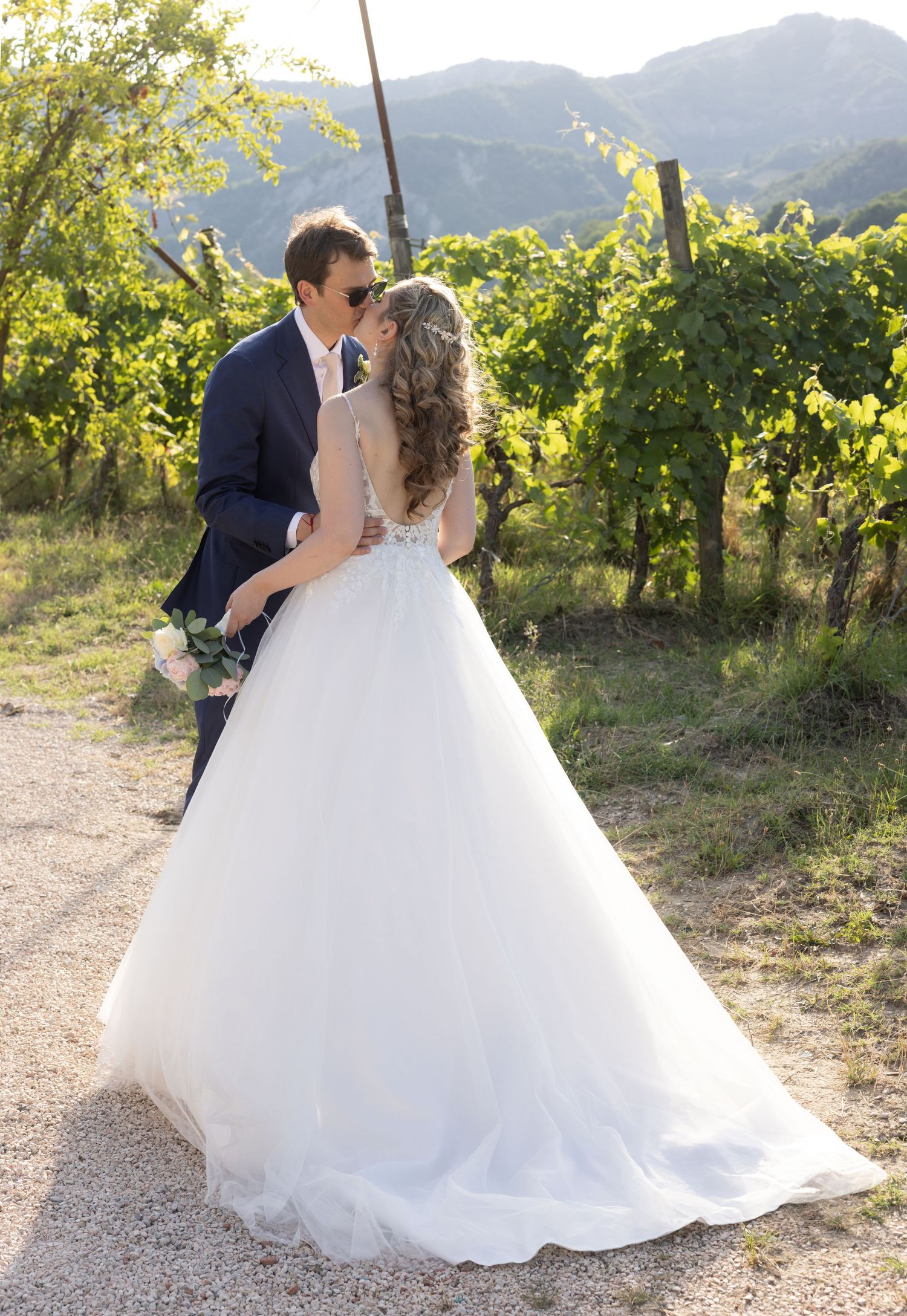 Romantic wedding portraits in a sun-lit vineyard with mountain landscape.