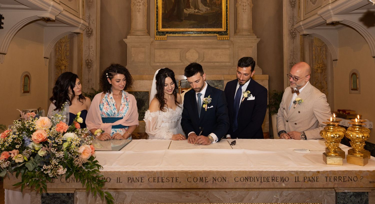 Wedding ceremony setup in an ornate church with floral decorations and guests.