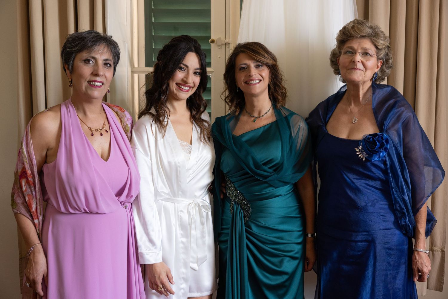 Wedding party members pose in coordinated dresses in various shades of blue and purple.