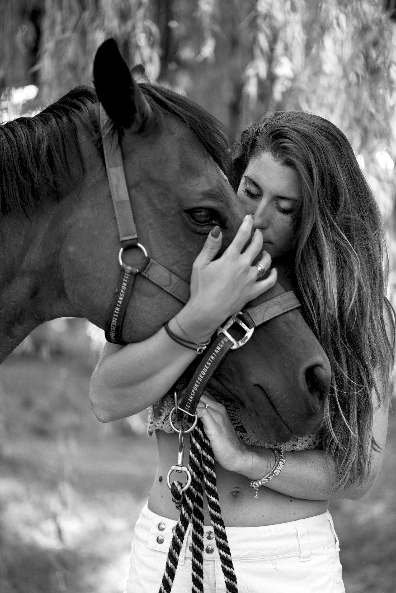 Black and white series showing tender moments between a horse and companion under trees.