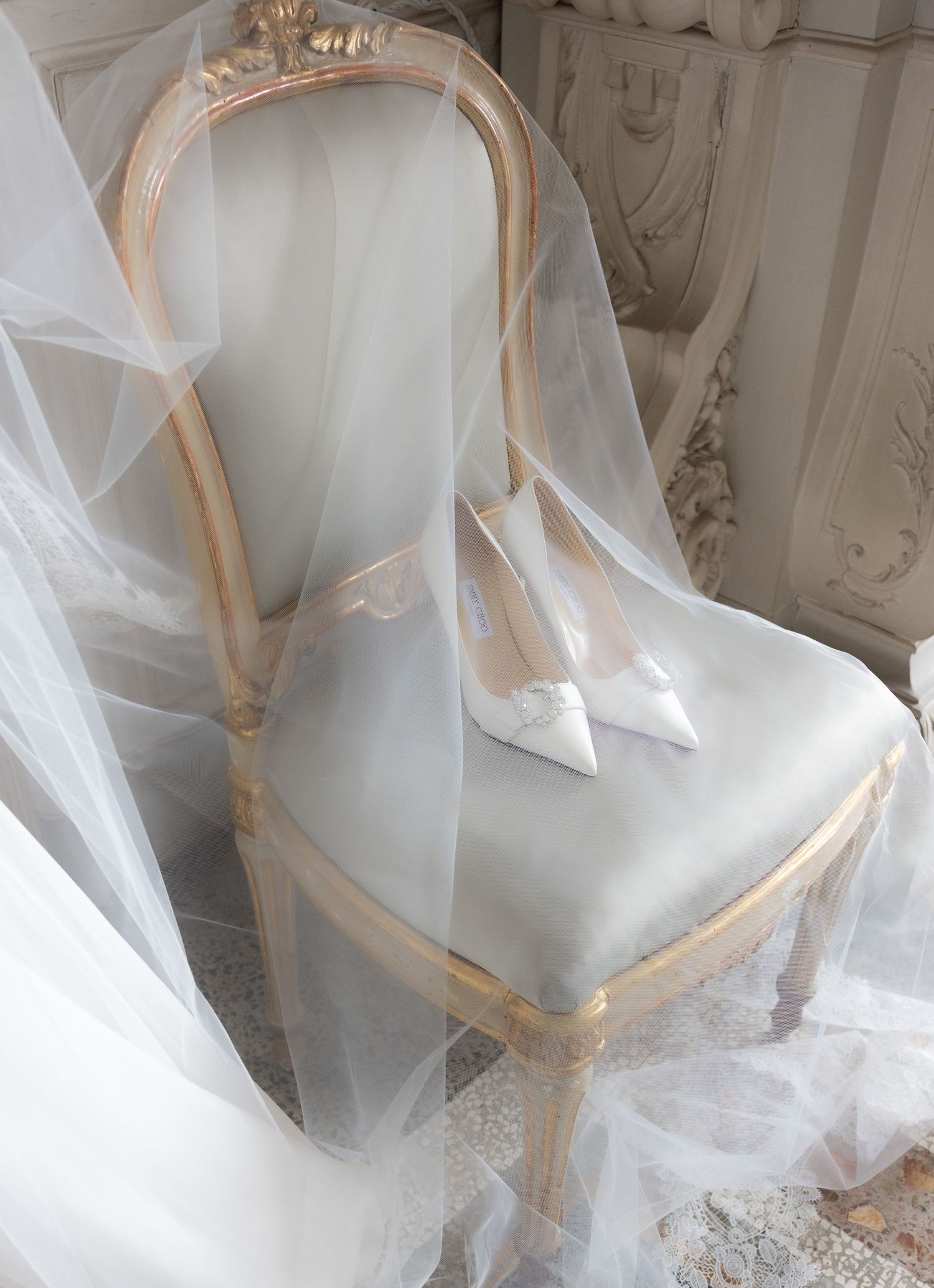 Close-up details of delicate white wedding dress fabric and tulle veil with intricate lace patterns.