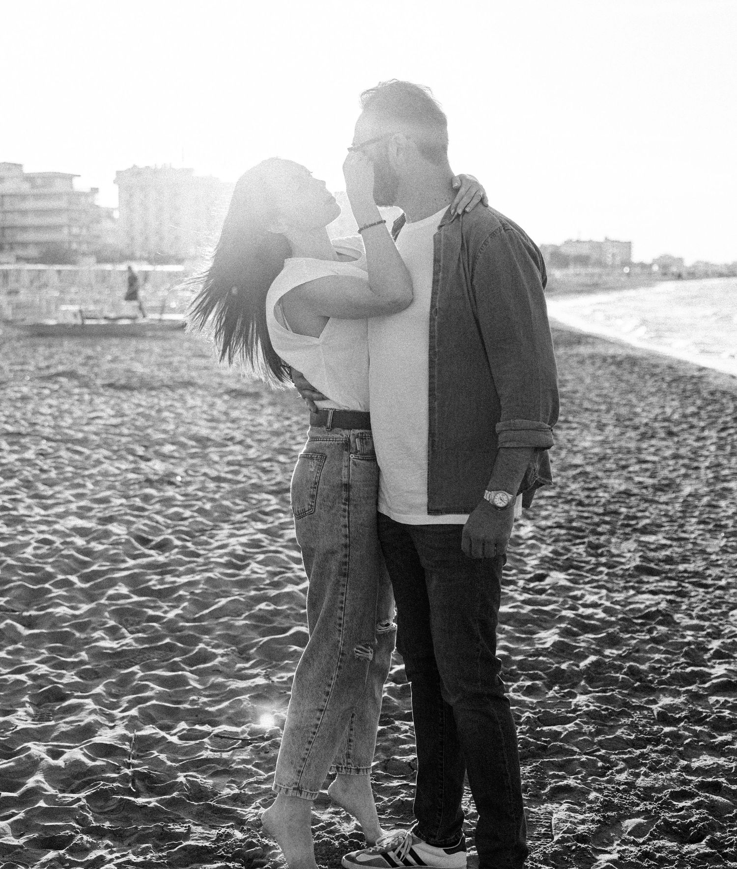 Couple walking together on a sandy beach in black and white photography.