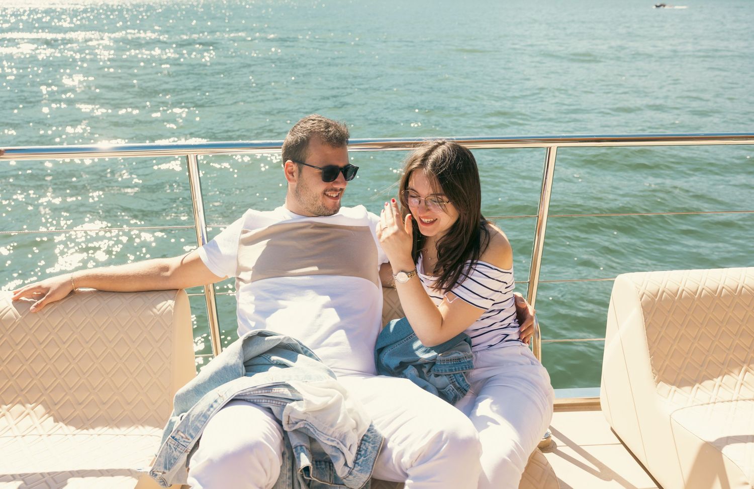 People enjoying leisure time on curved boat seating with sparkling water views.