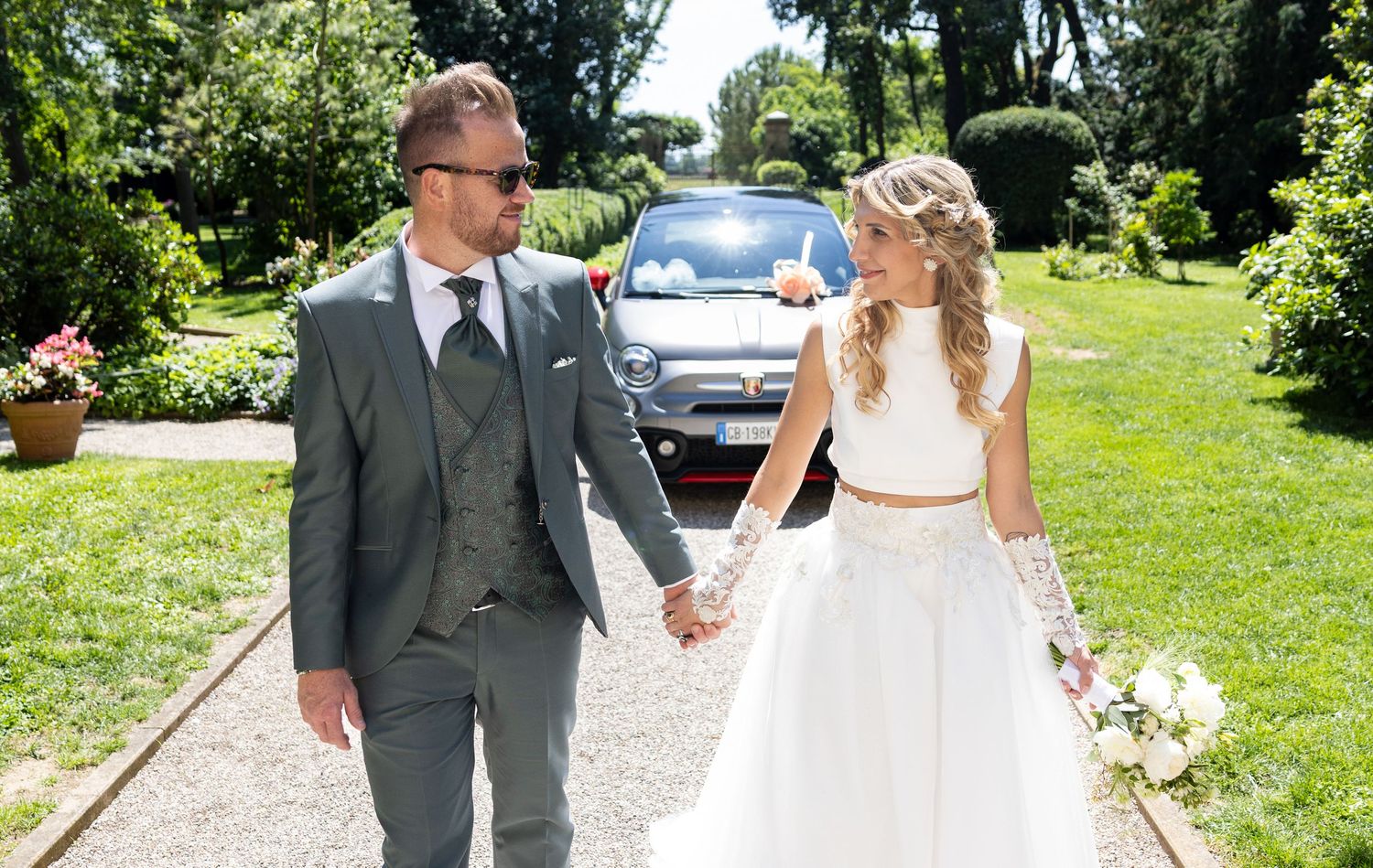 Newlyweds stroll together on a scenic garden pathway.