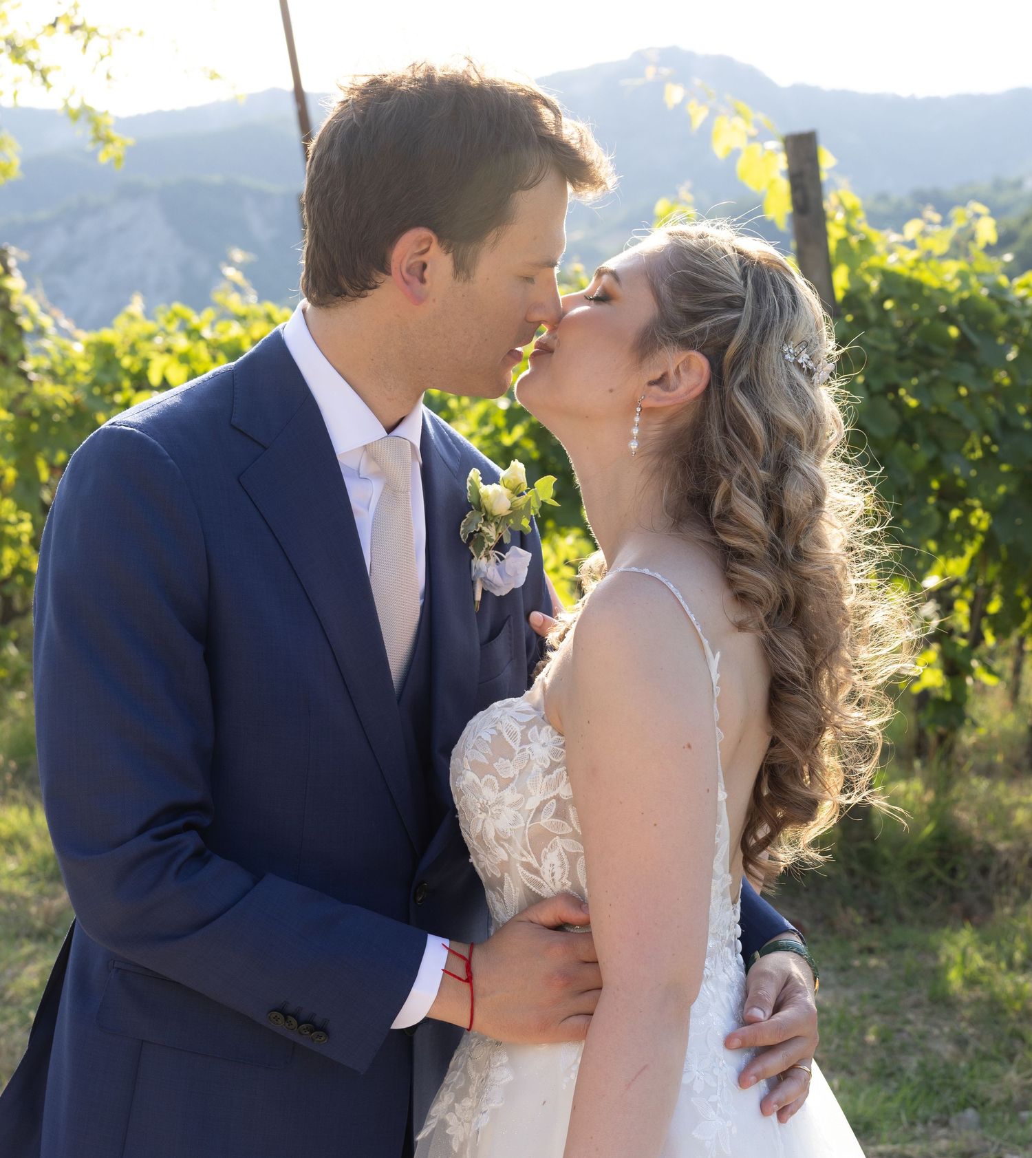 Intimate wedding moment captured in a scenic vineyard with mountains in the background.