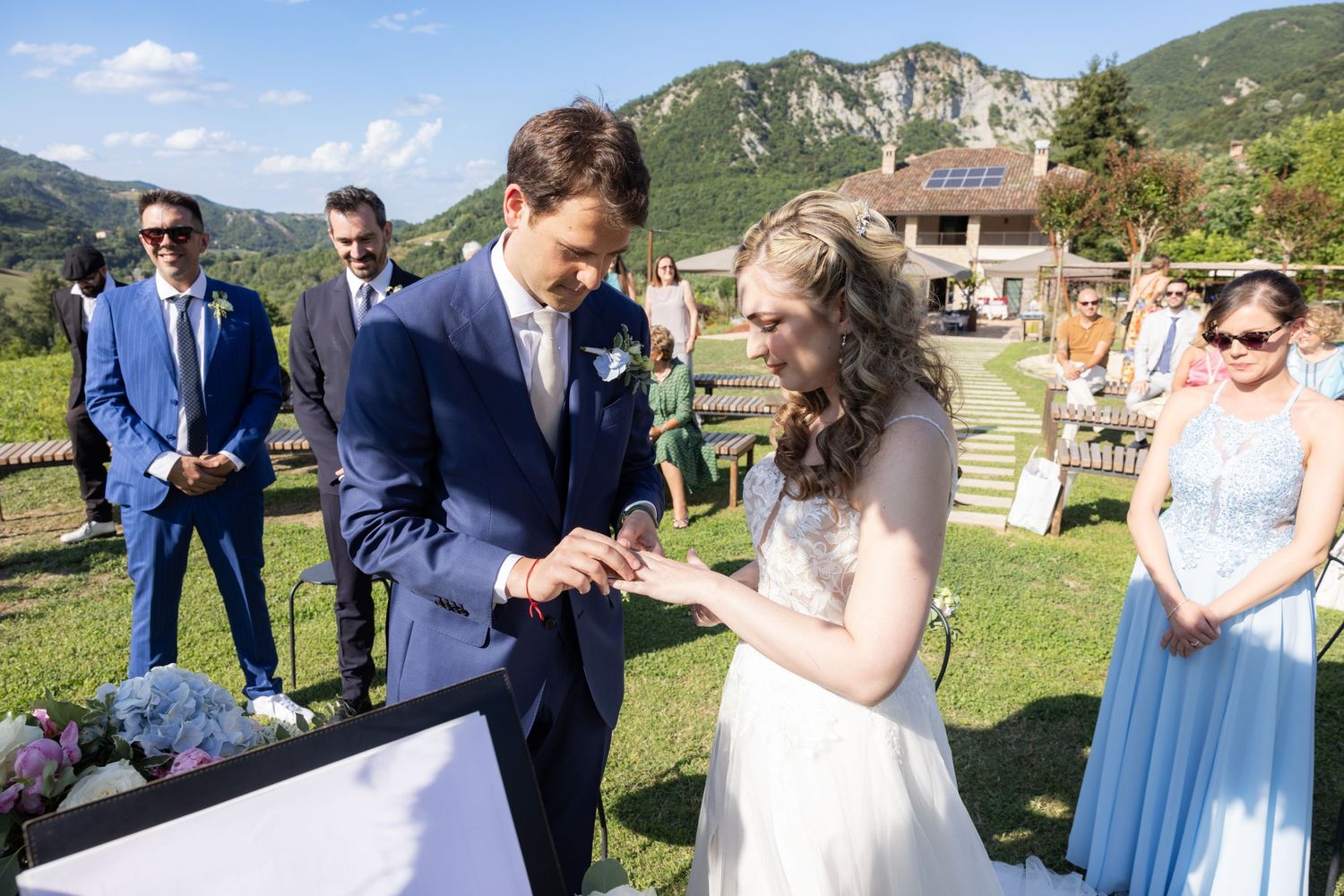 A couple participates in their ring exchange ceremony against a backdrop of mountain scenery.