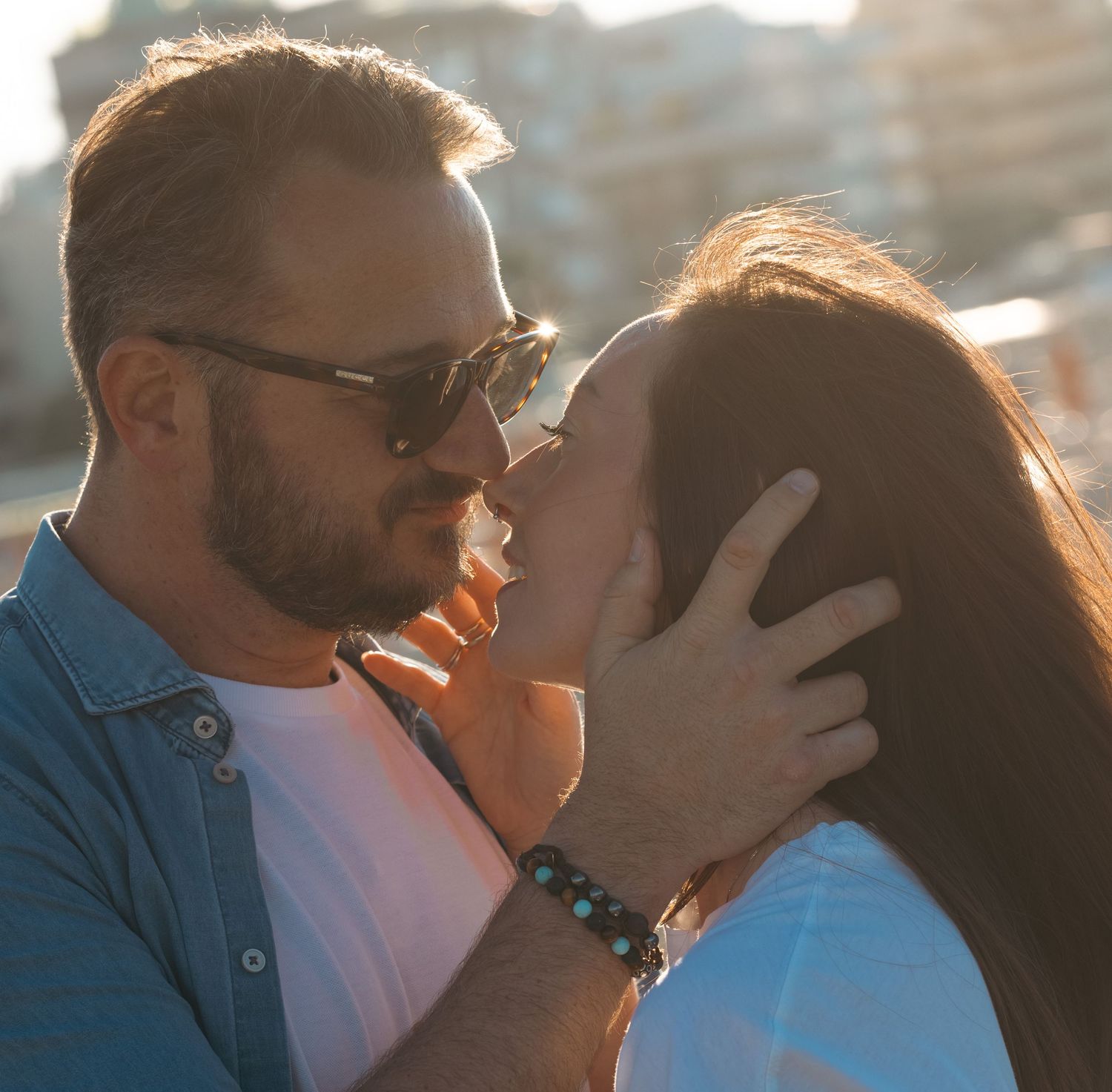 Intimate close-up of couple sharing a tender moment in golden sunlight.