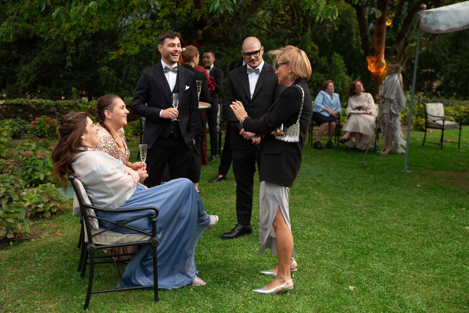 Wedding guests relaxing on a grassy lawn during outdoor reception.