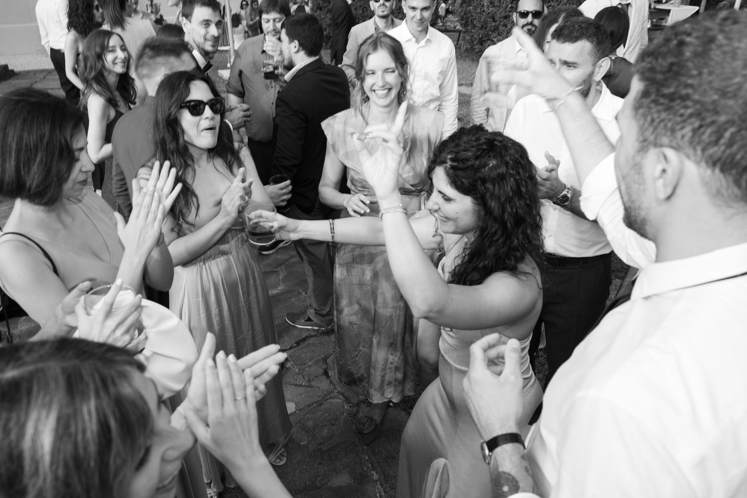 Wedding guests dancing and celebrating at an outdoor reception.