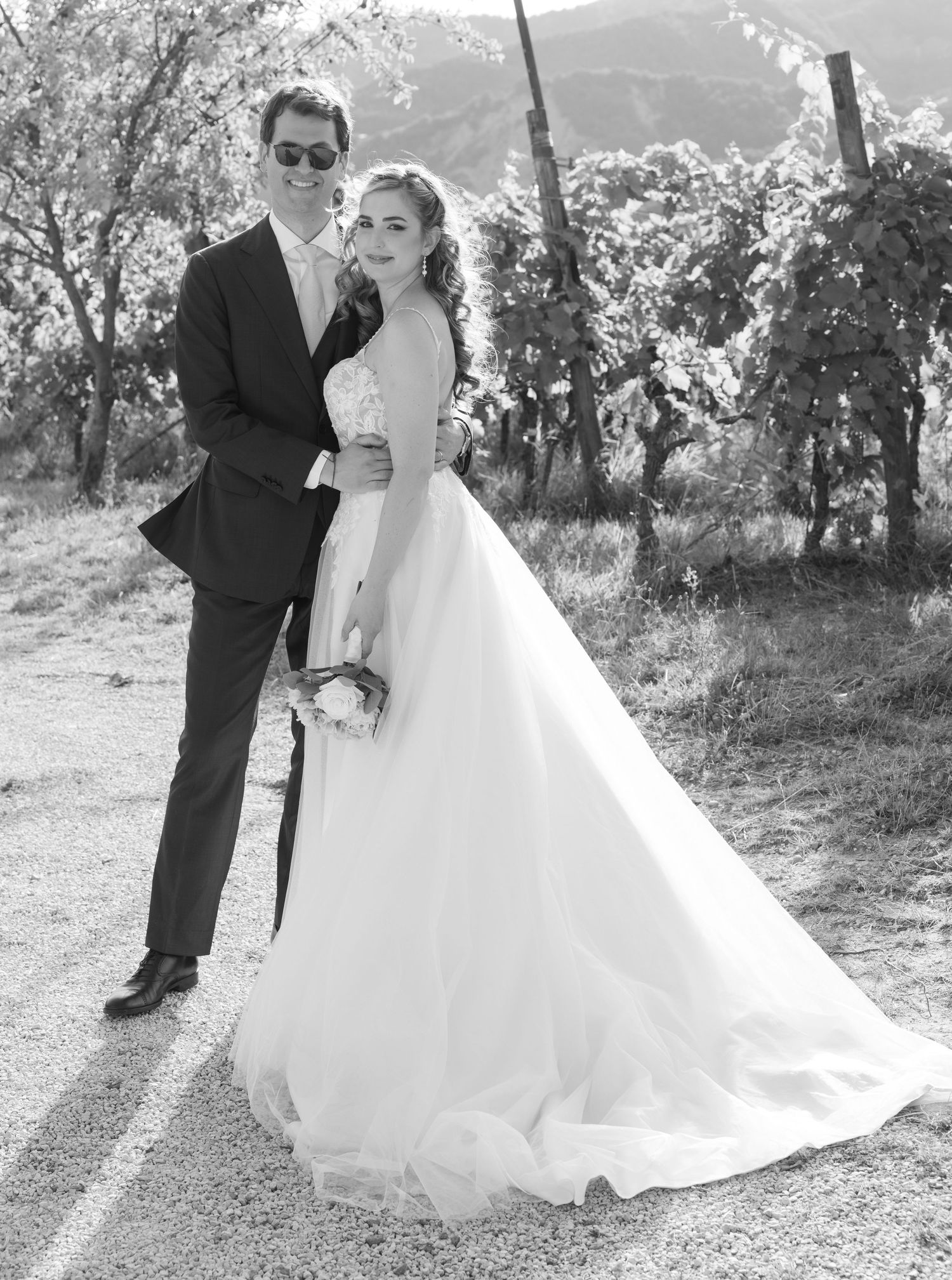 Black and white wedding portraits captured in a rustic vineyard setting.