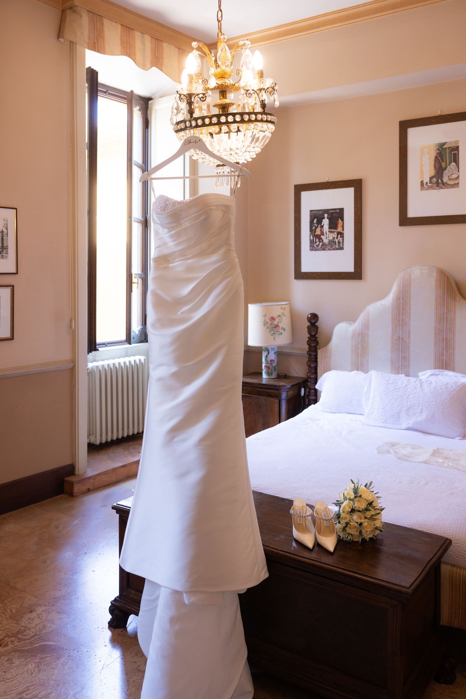 Elegant hotel room interior with chandelier, white linens, and classic wooden furniture showcasing warm lighting.